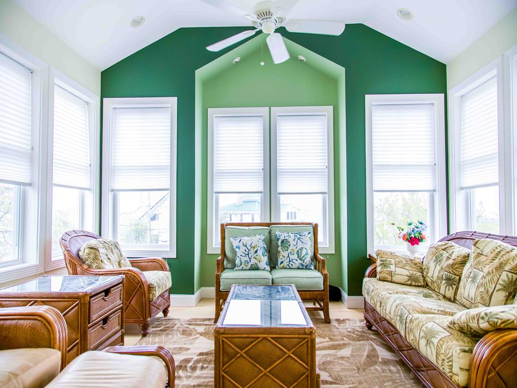 image Sunlit family lounge featuring bold green walls, wicker furniture, and vaulted ceilings—perfect for group gatherings.