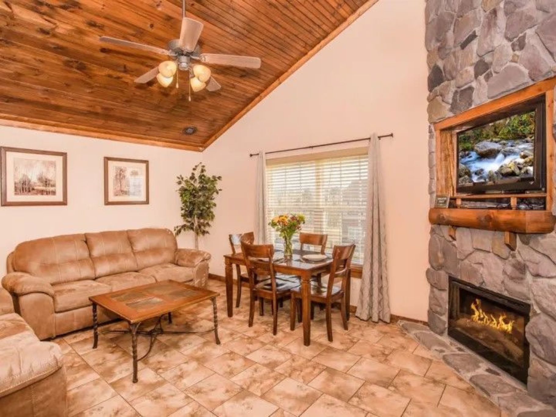 image Living room with sofa, fireplace, and dining table under a vaulted wood ceiling.