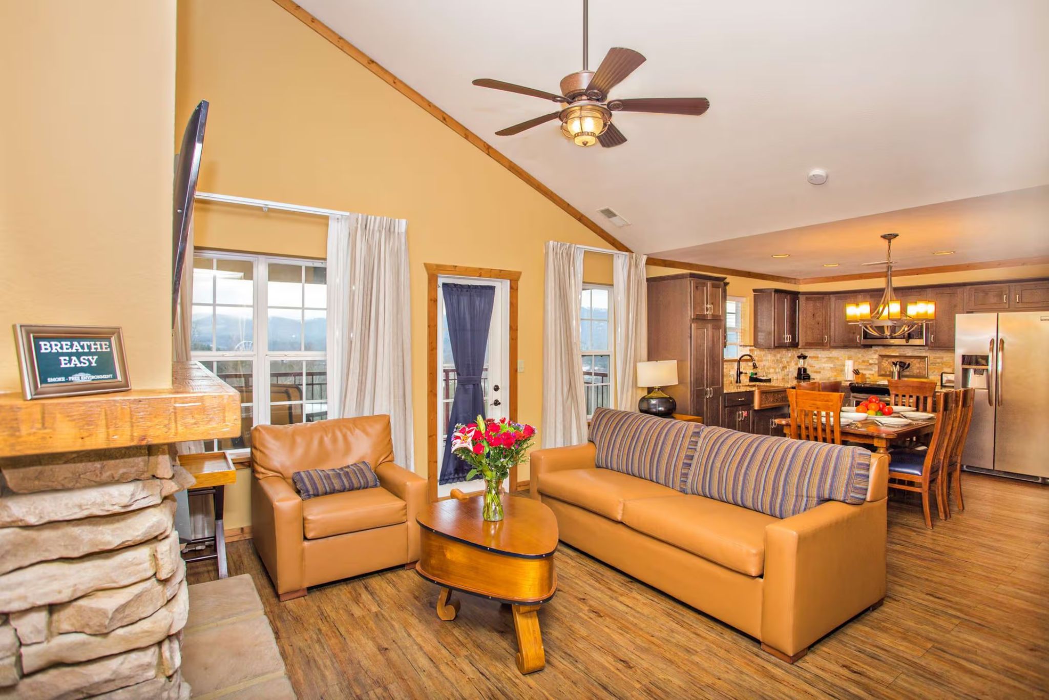 image Open-concept living area with sofa seating, fireplace, and TV in a cozy mountain style.