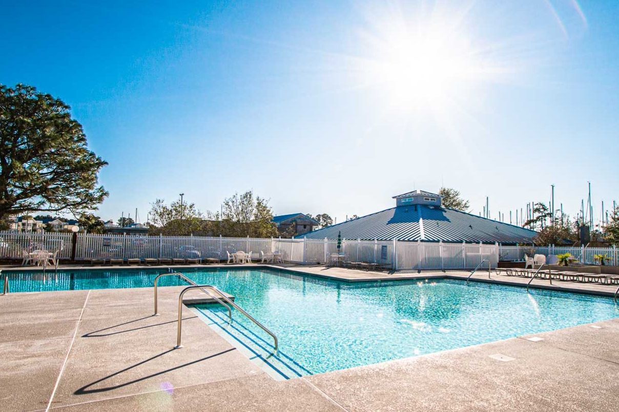 image Enjoy a refreshing dip in the sparkling outdoor pool, surrounded by lush trees and a clear blue sky.