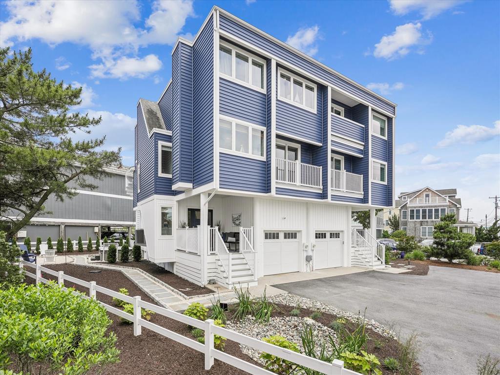 image This striking blue beach townhome boasts multiple balconies and expansive windows, inviting natural light and showcasing the vibrant coastal scenery just steps away from the shore.