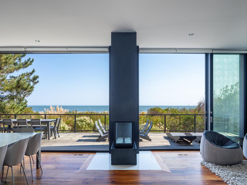 image The living area boasts panoramic ocean views framed by large glass walls, creating a serene space centered around a sleek modern fireplace.