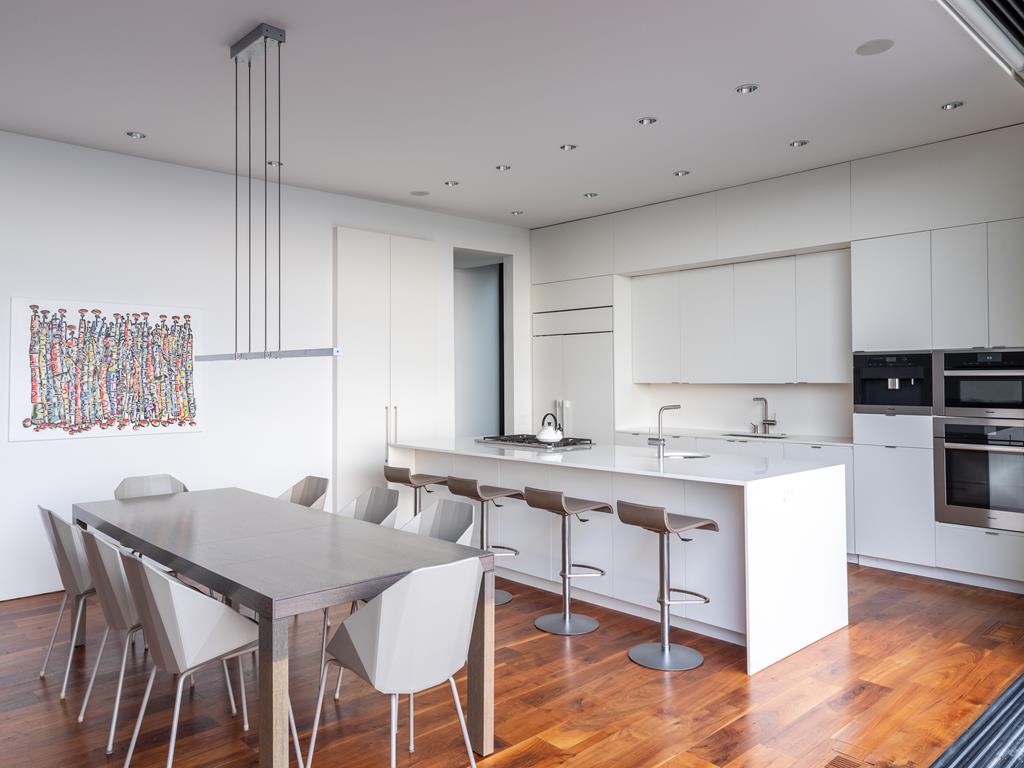image The well-designed kitchen features minimalist design elements and a functional layout, highlighted by ample natural light from the large windows.