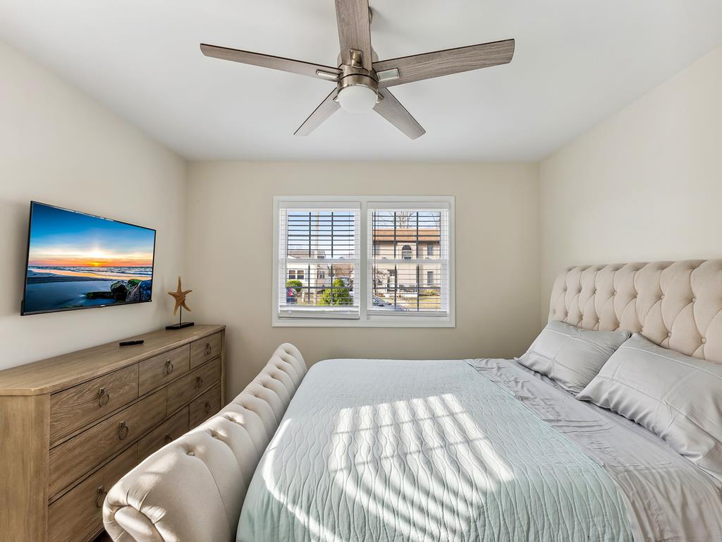 image A closer look at the bedroom shows a tufted bed, modern dresser, and soothing color palette that creates an inviting atmosphere.