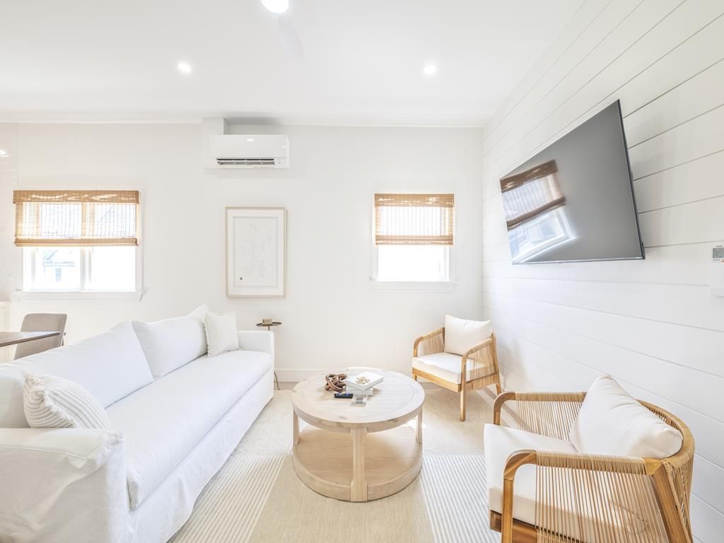image Living room with woven chairs, shiplap accent wall, and wall-mounted TV.