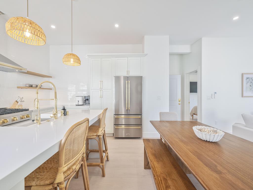 image Bright, modern kitchen with bar seating, gold fixtures, and open shelving.