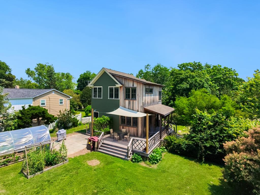 image A charming restored farmhouse surrounded by lush greenery, showcasing its inviting exterior and well-maintained landscaping.