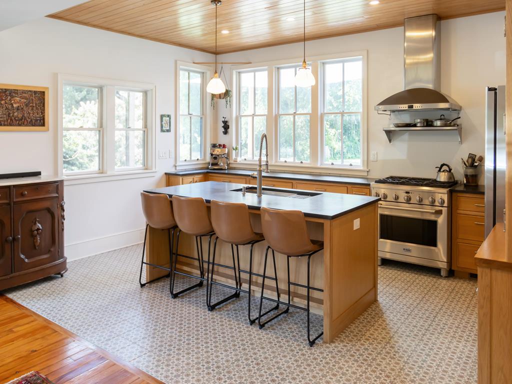 image A modern kitchen featuring warm wood accents, sleek appliances, and ample natural light streaming through large windows.
