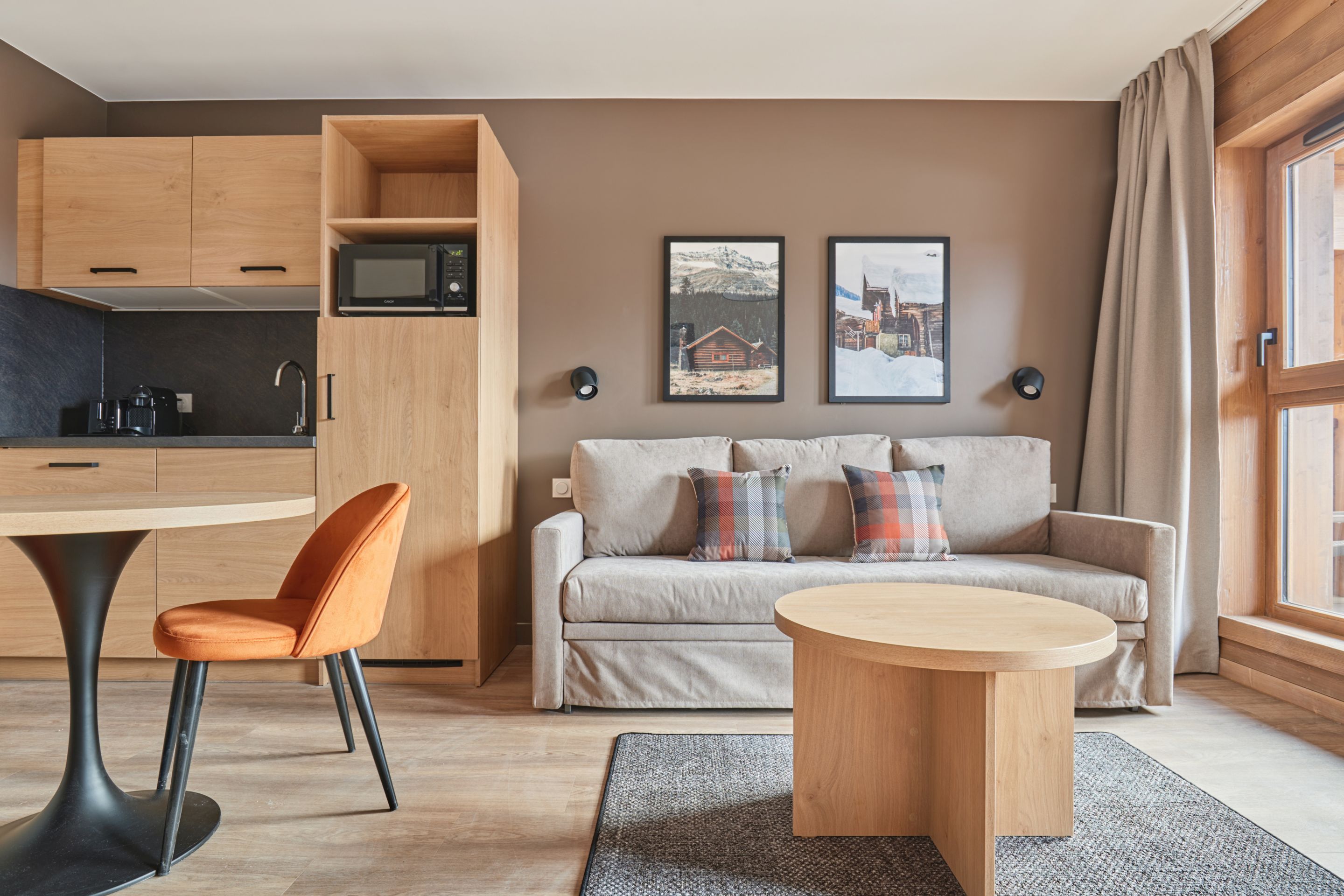 image Dining area with round table and orange chairs in view — a compact, functional layout for meals after a day on the slopes.