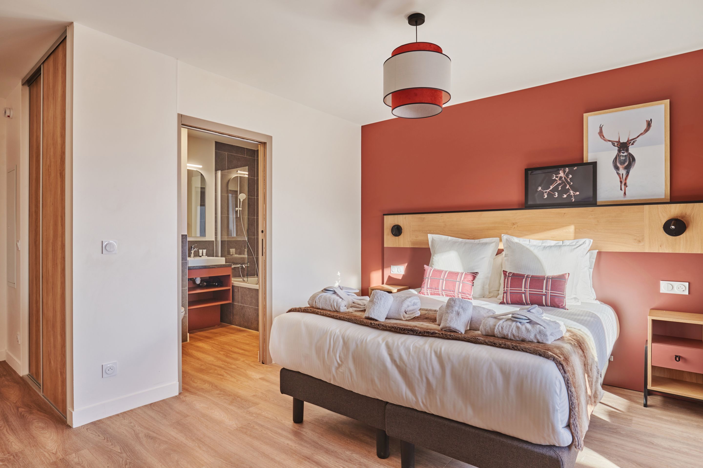 image Double bed with warm red walls and wooden headboard — bed linen is included in every stay.