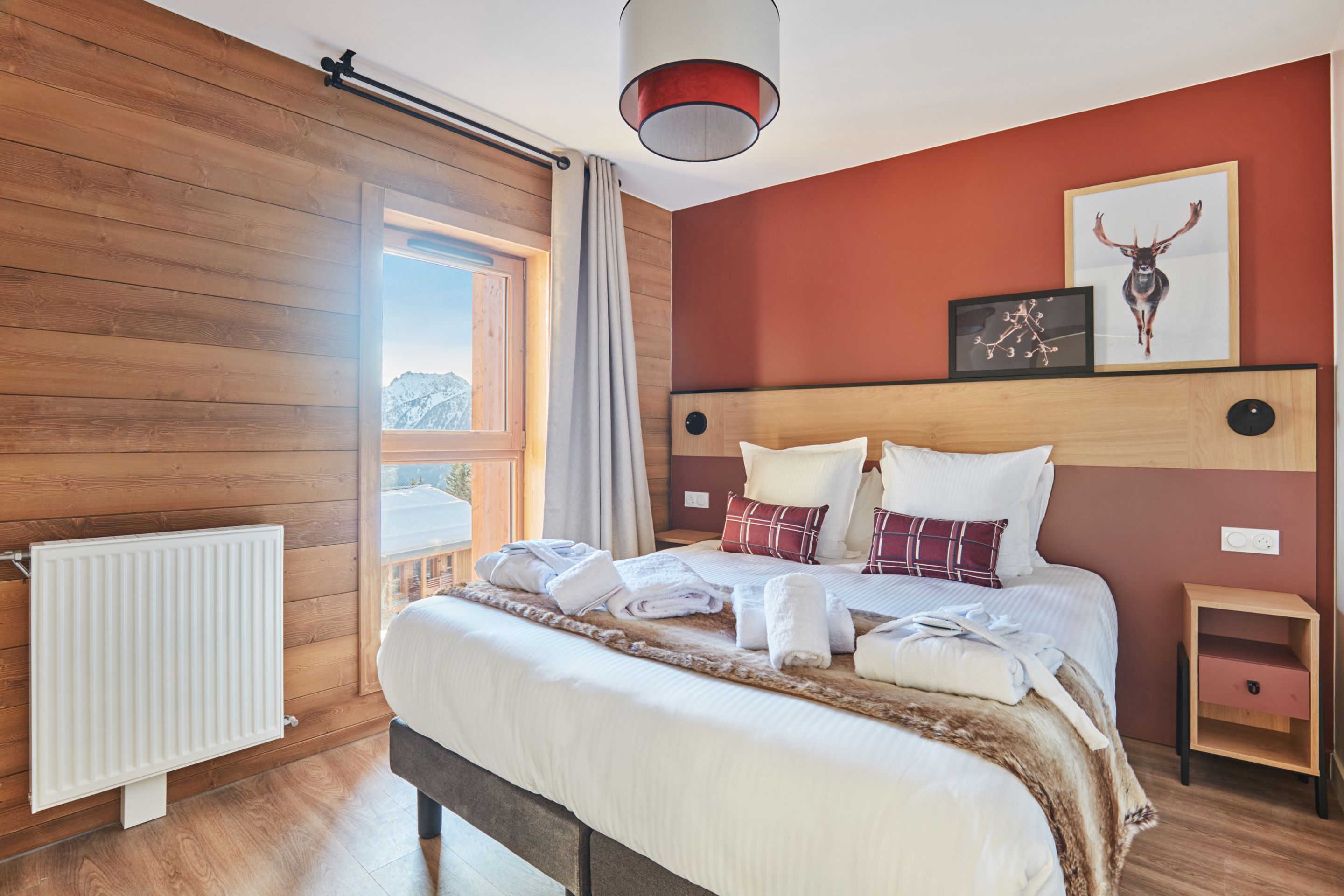 image Bedroom with a double bed, terracotta walls, and a mountain view through the window — bed linen included.