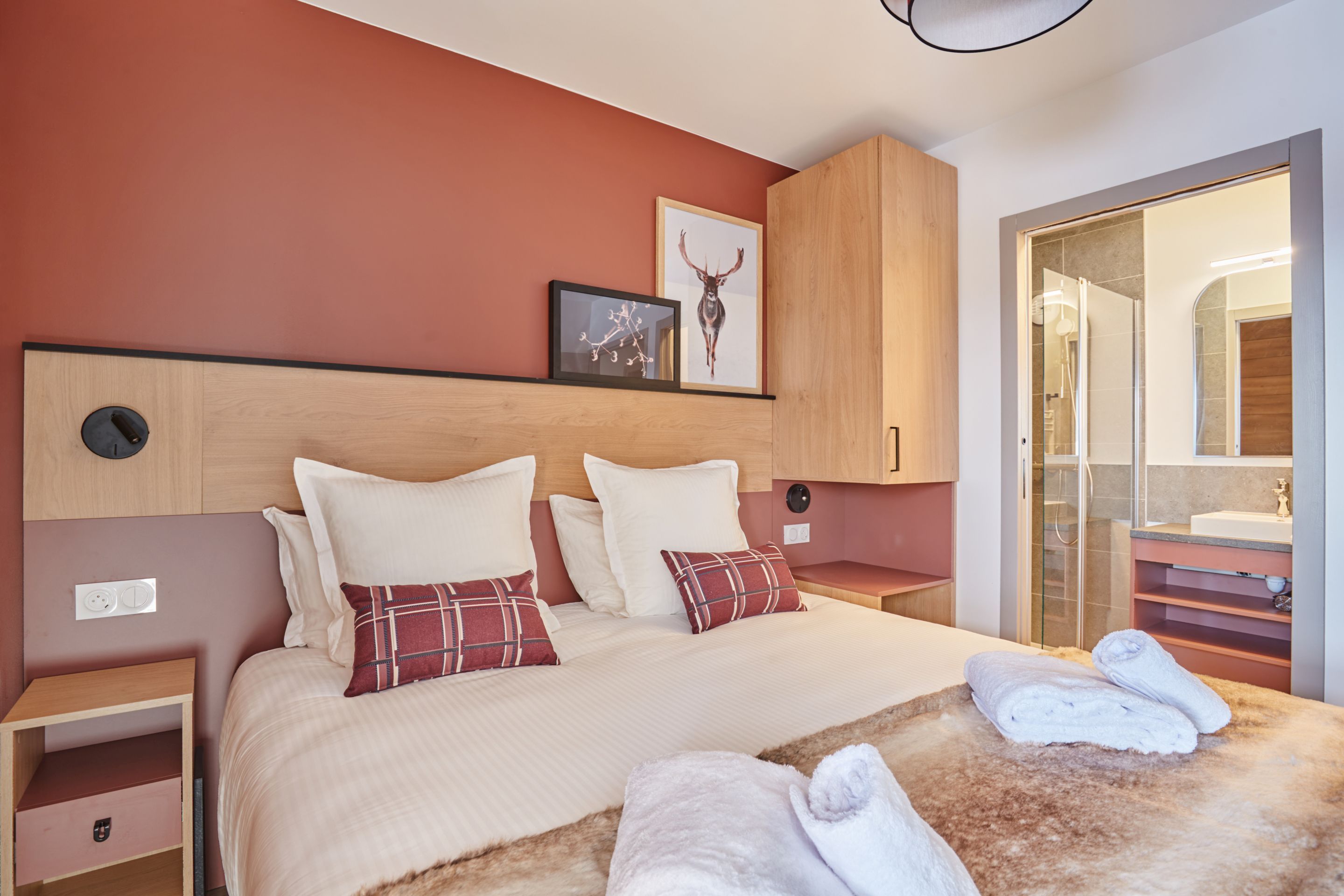 image Double bedroom with terracotta walls, wooden headboard, and white linens — a warm retreat after a day on the San Bernardo slopes.