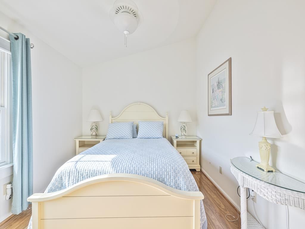 image Bright and airy bedroom featuring a queen bed, twin nightstands, and beachy décor.