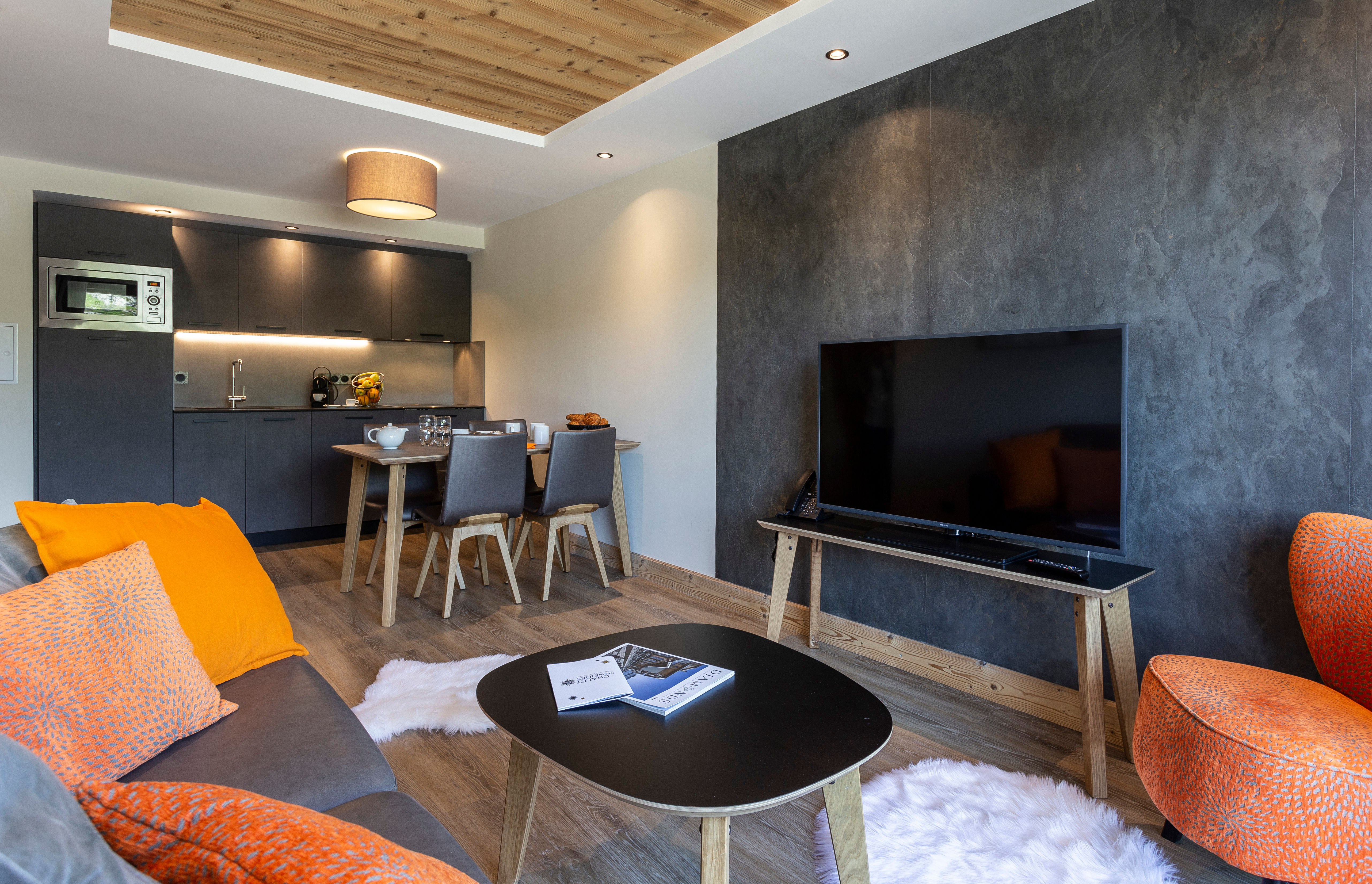 image The stylish living area showcases a modern design with warm textures, a comfortable sofa adorned with vibrant pillows, and a sleek kitchen equipped for intimate meals.