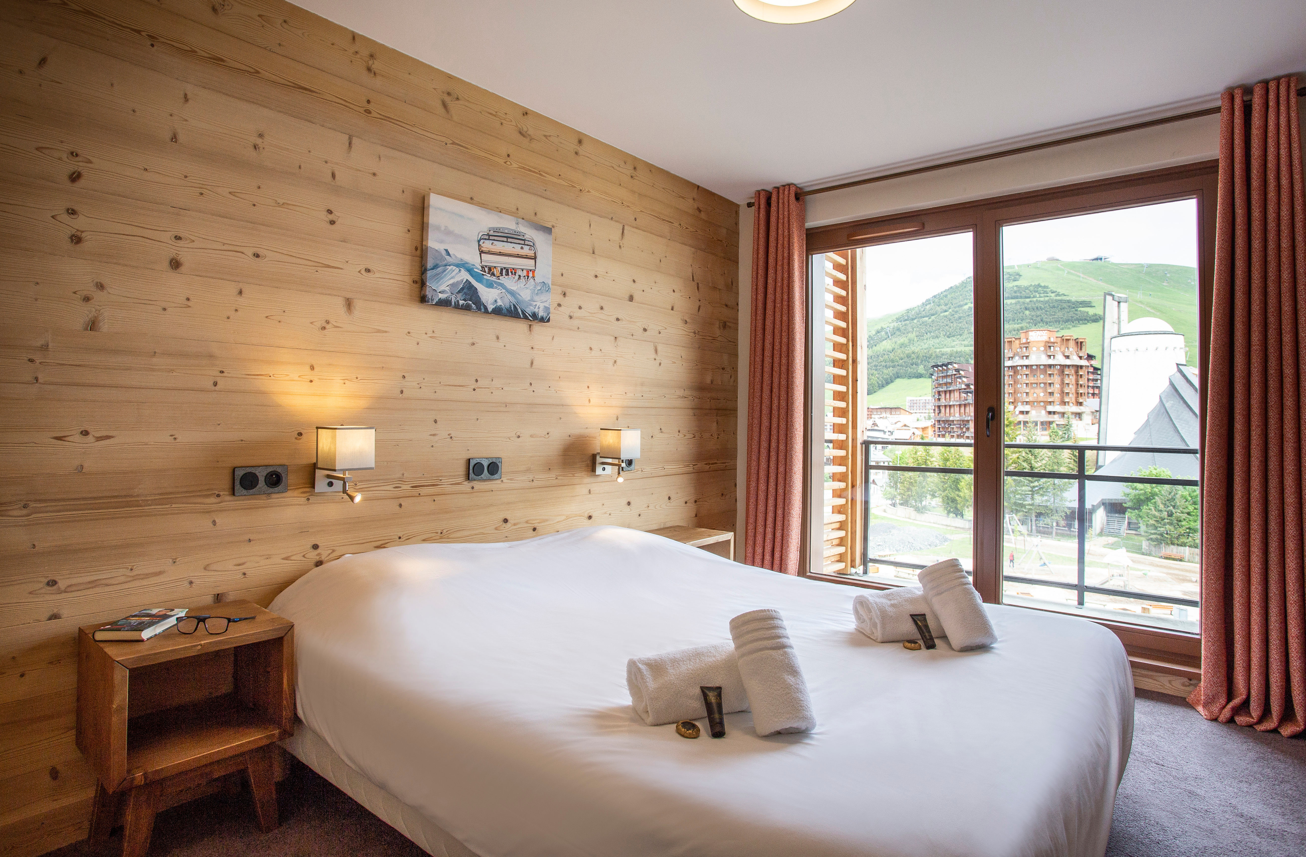 image The double bedroom boasts warm wood paneling and soft lighting, creating a tranquil retreat with picturesque views of the surrounding mountains from its private balcony.