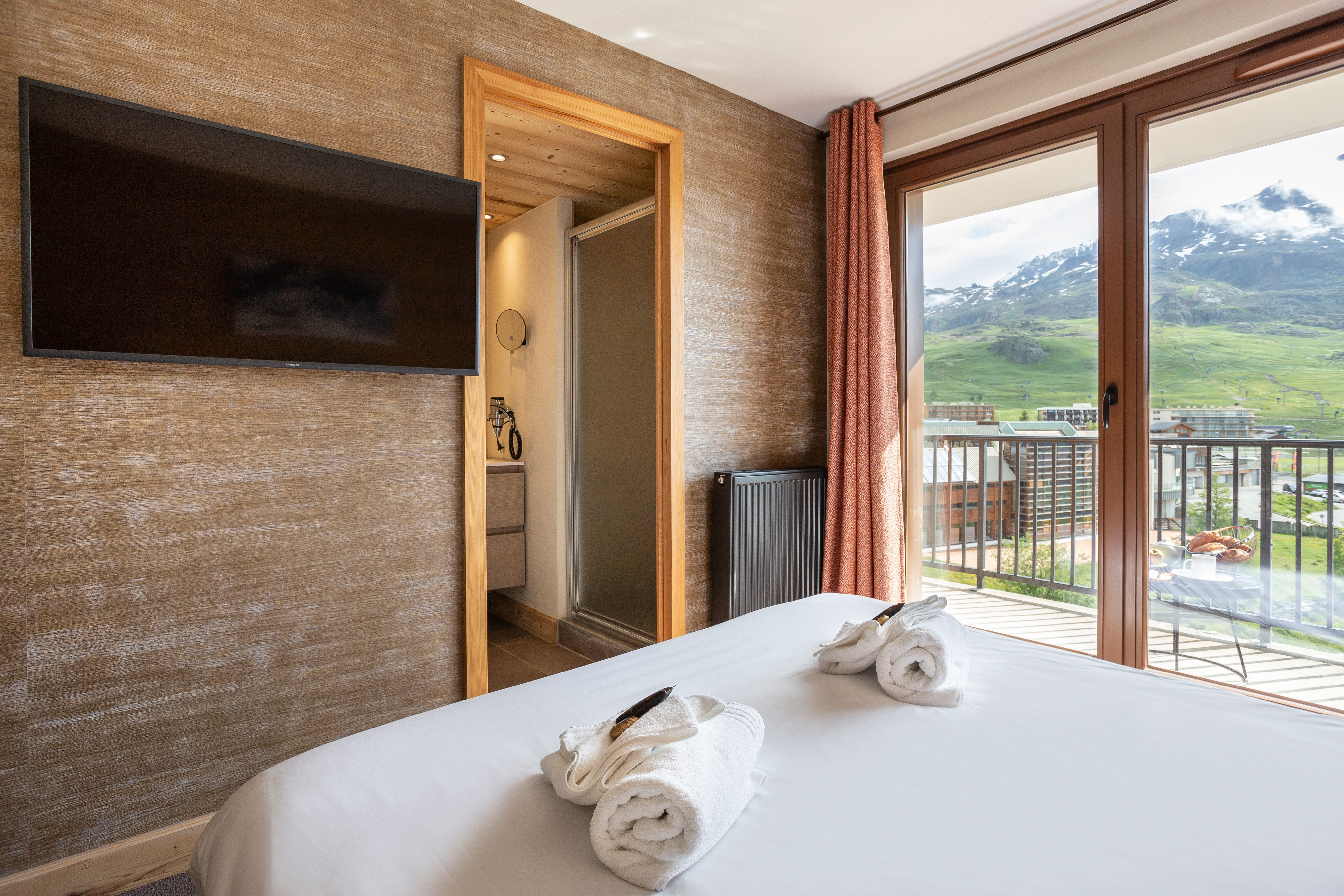image Wake up to the mountains in this warm wood-clad bedroom with balcony access.