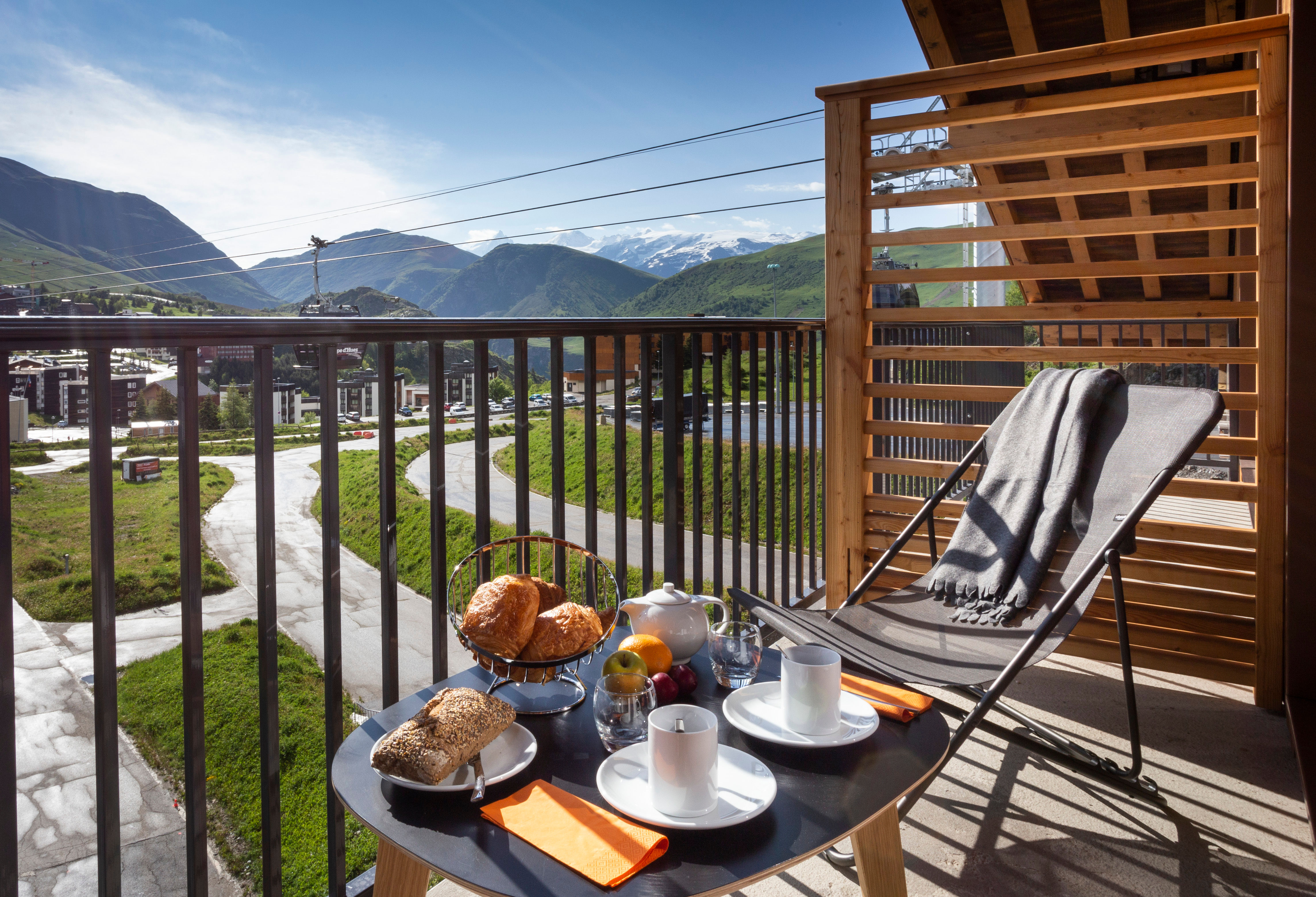 image Charming balcony setup with sun loungers and breakfast tray overlooking breathtaking alpine peaks.