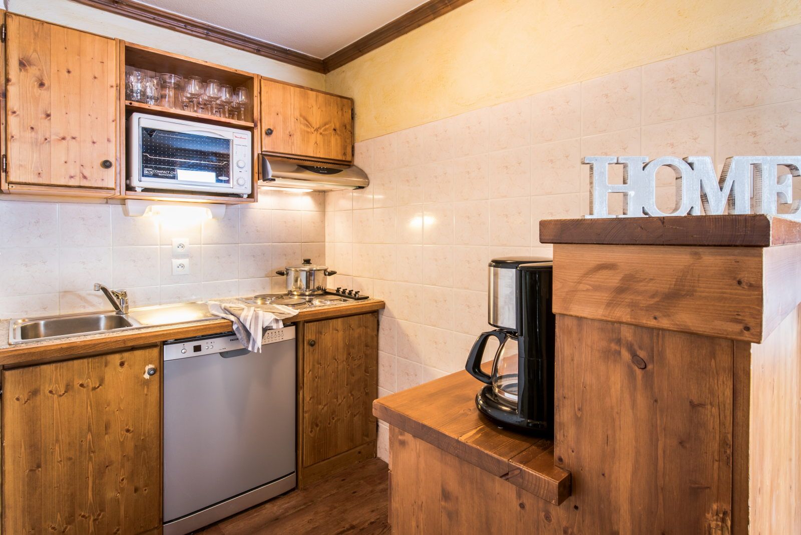 image Kitchen with wooden cabinets, sink, and essential appliances — ready for self-catered meals