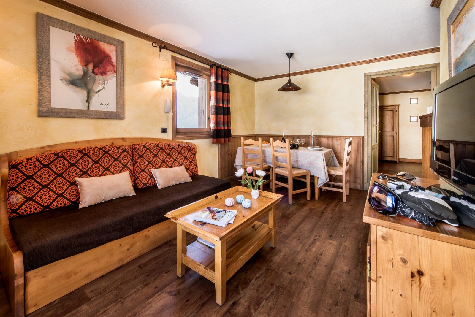 image Living area with a sofa, dining table, and bright floral artwork on the walls