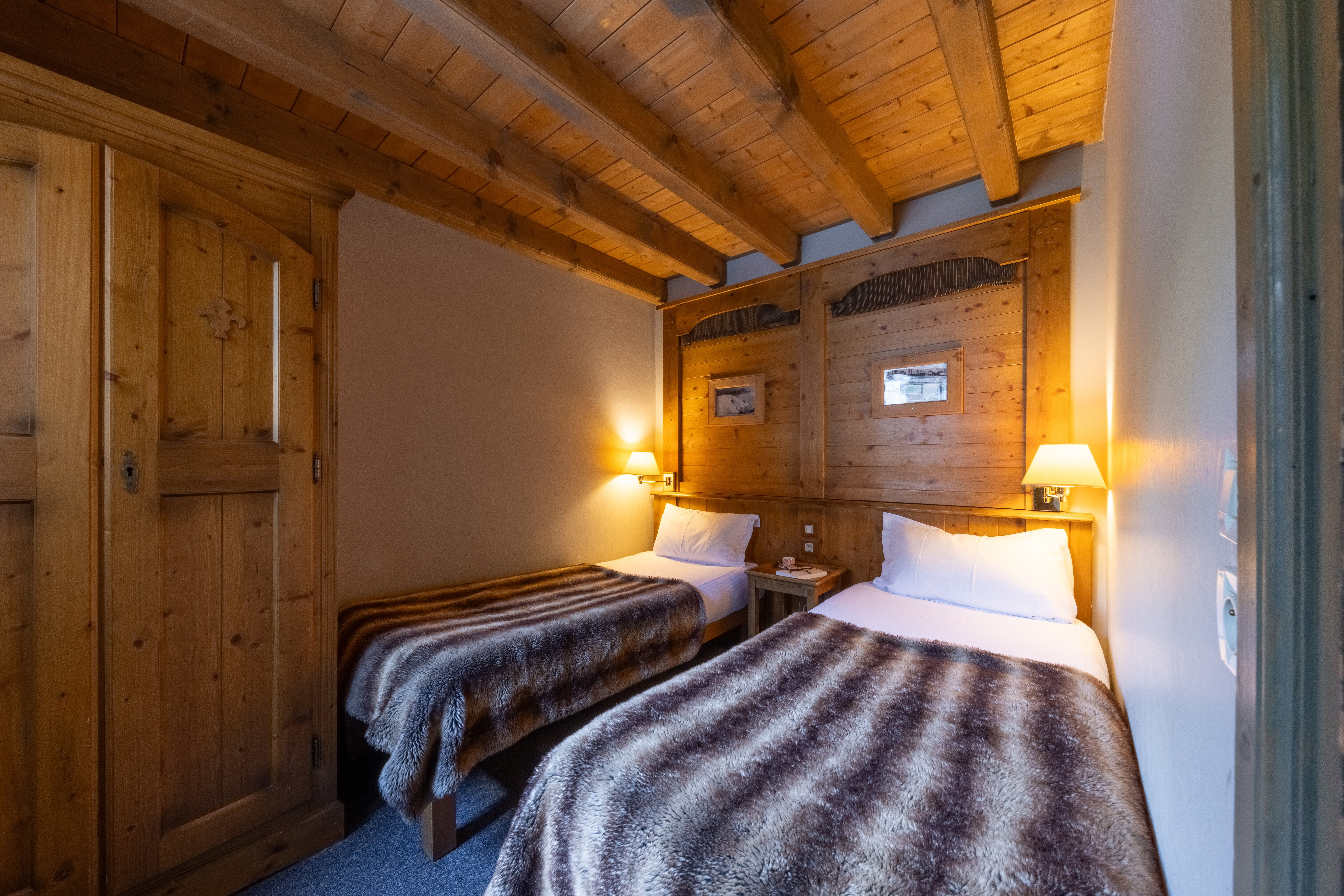 image Bedroom with wooden panelling, two beds, and a welcoming bedside setup