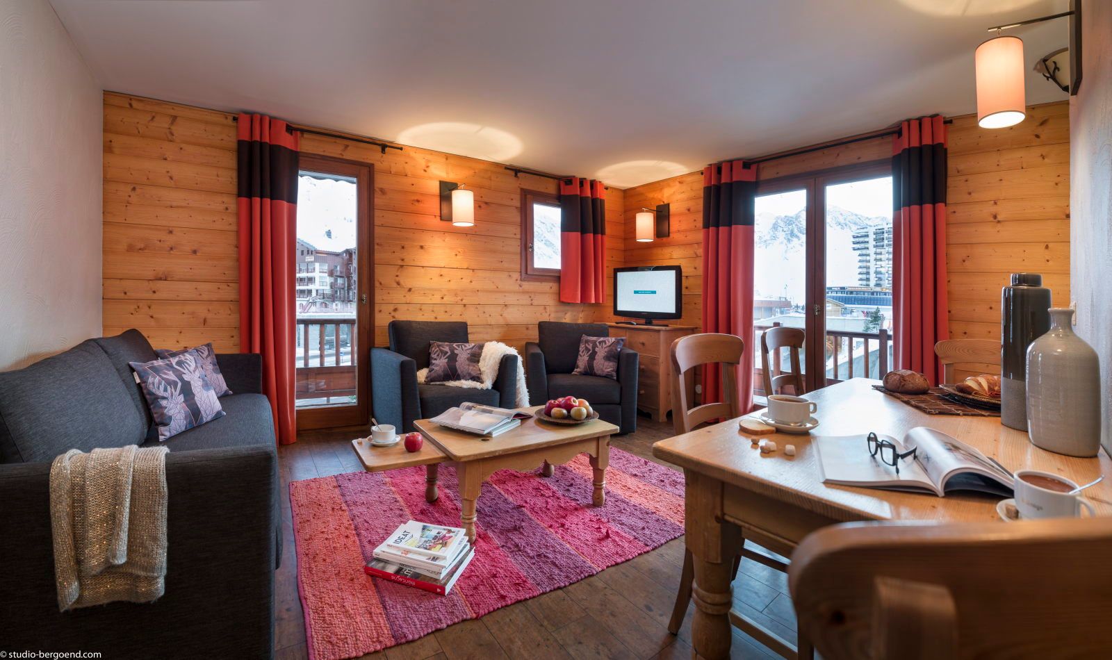 image Light-filled living space with a dining table, two sofas, and framed windows with a view