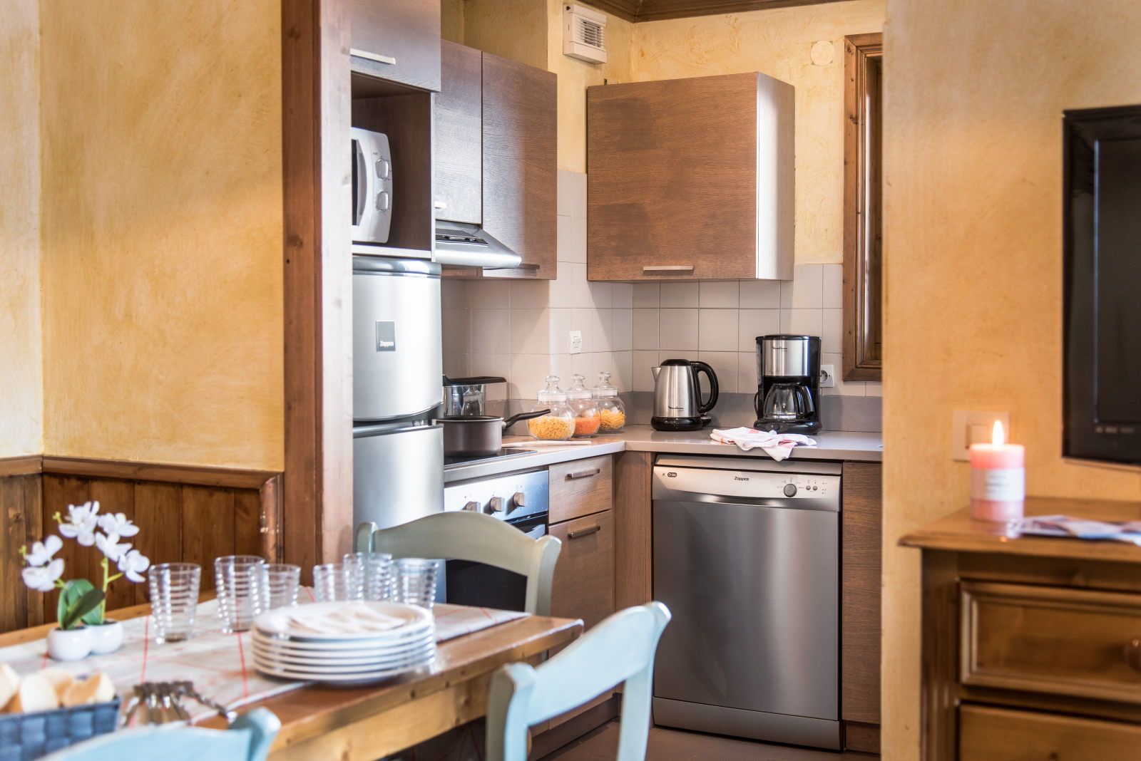 image Compact kitchen with stainless steel appliances, wooden cabinets, and a dining table ready for meals