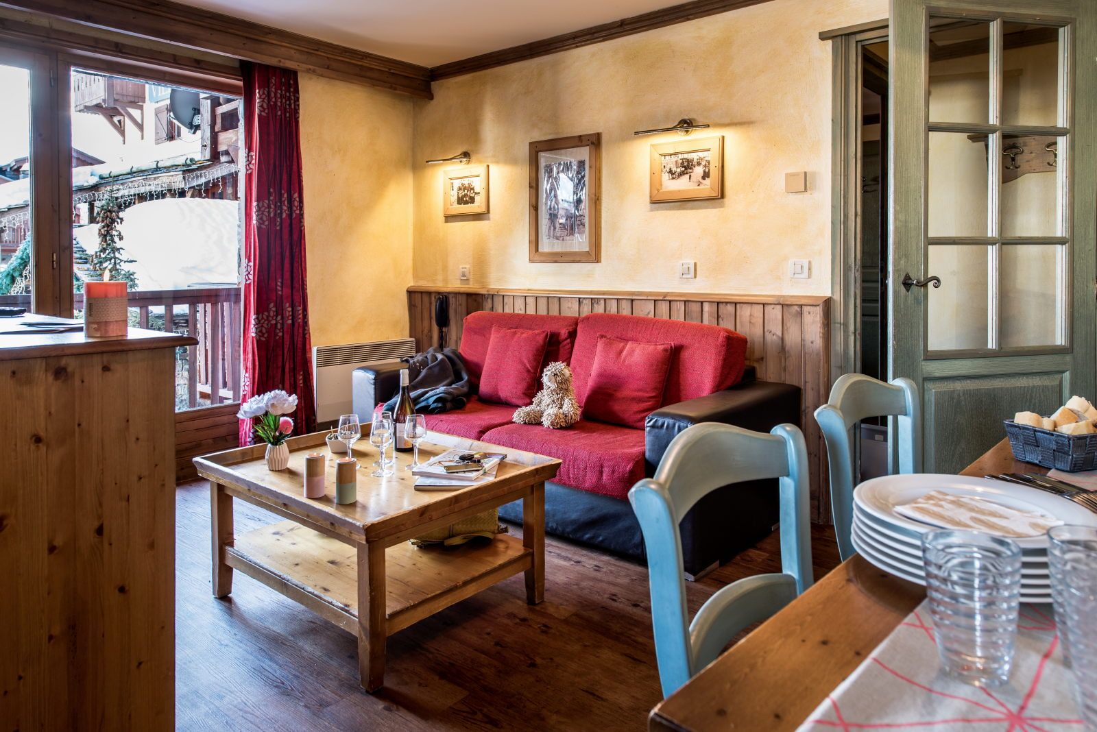 image Living area with large windows, a red sofa, and candles on the table for a cosy atmosphere