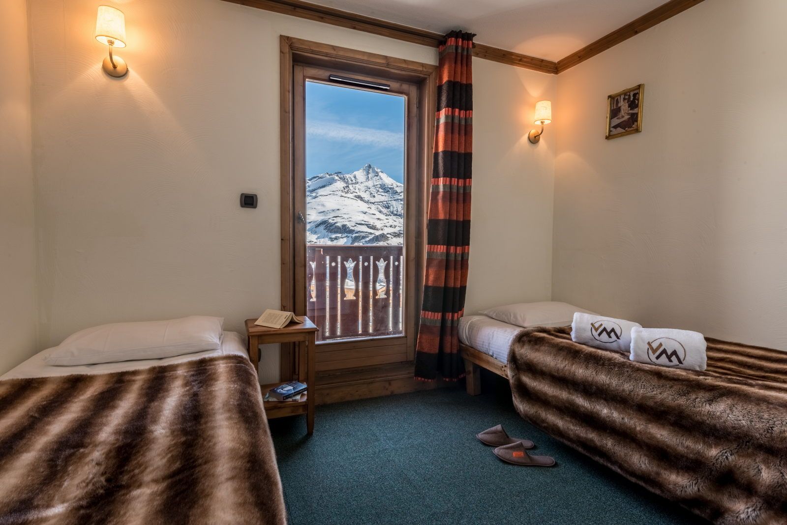 image Twin bedroom with mountain views through the window, warm lighting, and decorative curtains