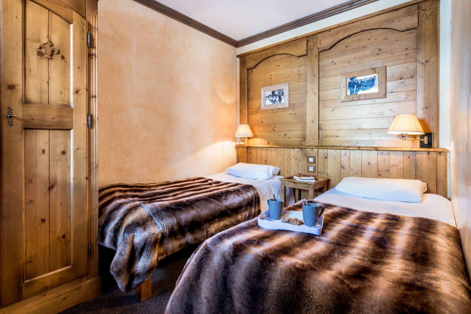 image Twin bedroom with two plush beds, warm blankets, and framed artwork on the walls