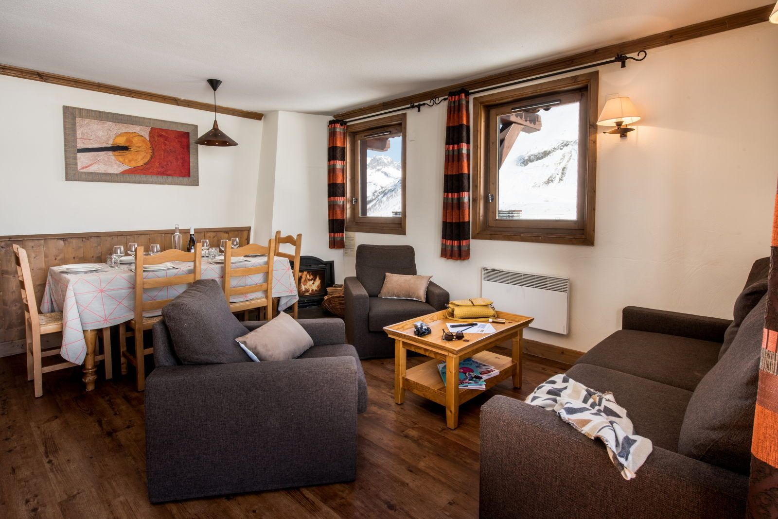 image Living area with a dining table, grey sofas, and large windows bringing in the mountain light