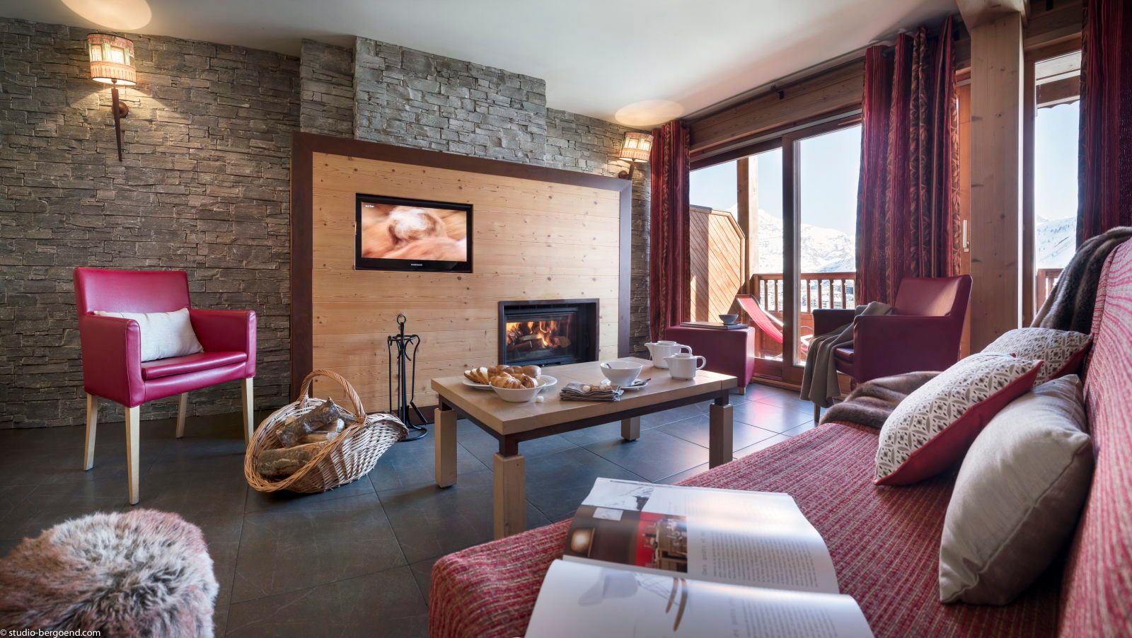 image Living area with red armchairs, a fireplace, and a coffee table set with refreshments