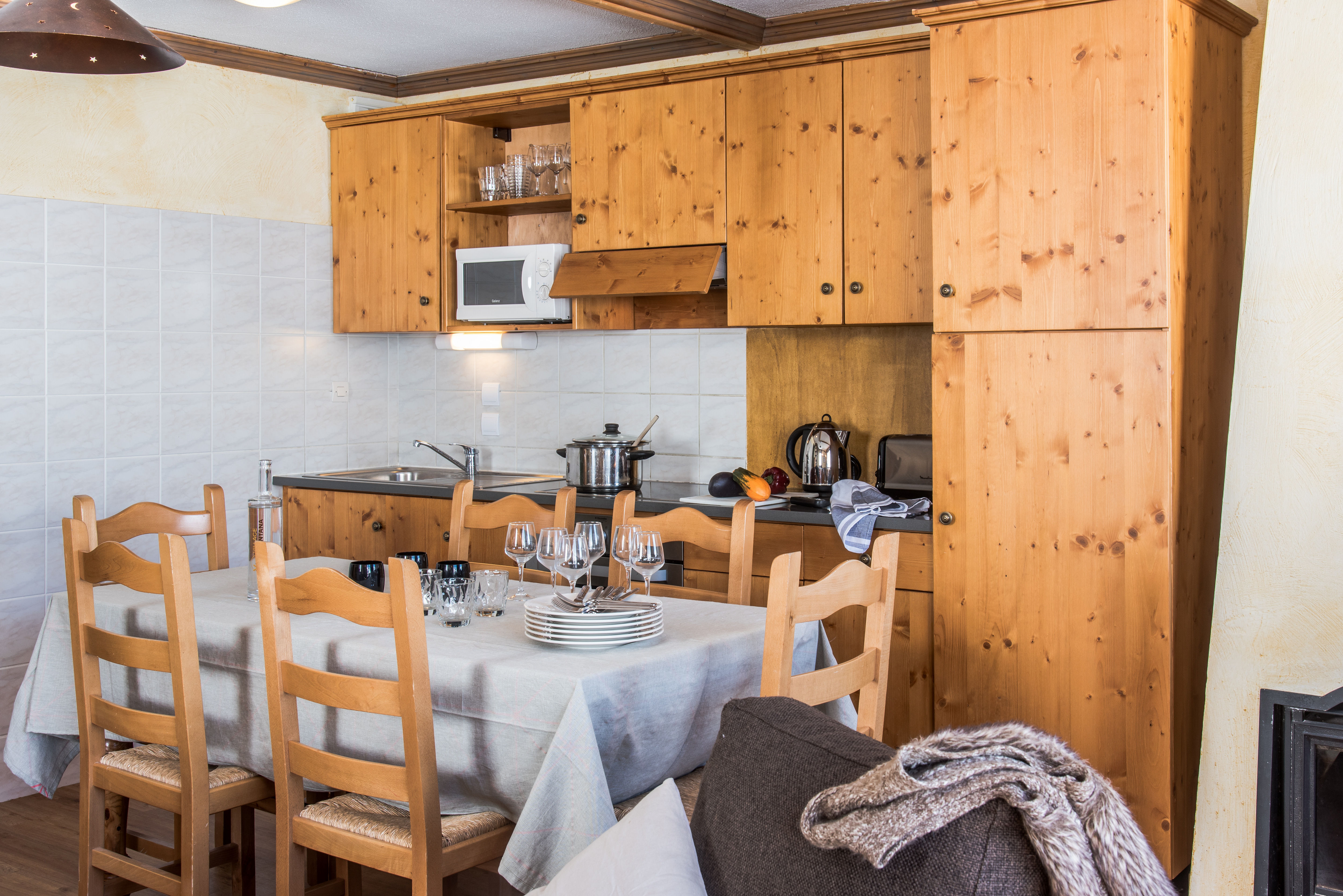 image Fully equipped kitchenette with wooden cabinetry and cozy dining table.