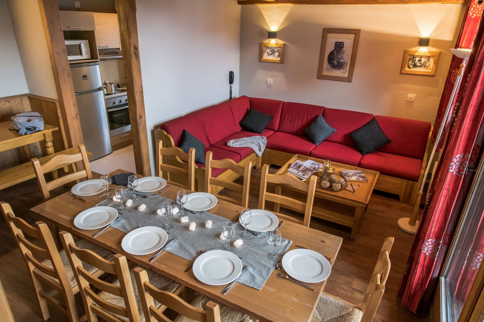 image Open living space with a dining area, kitchen appliances, and a red sofa for relaxed evenings