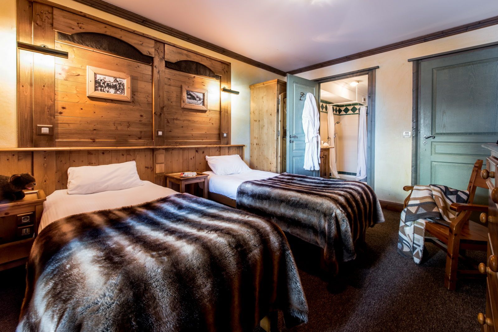 image Bedroom with two beds, wooden accents, and a small bathroom entrance for added convenience