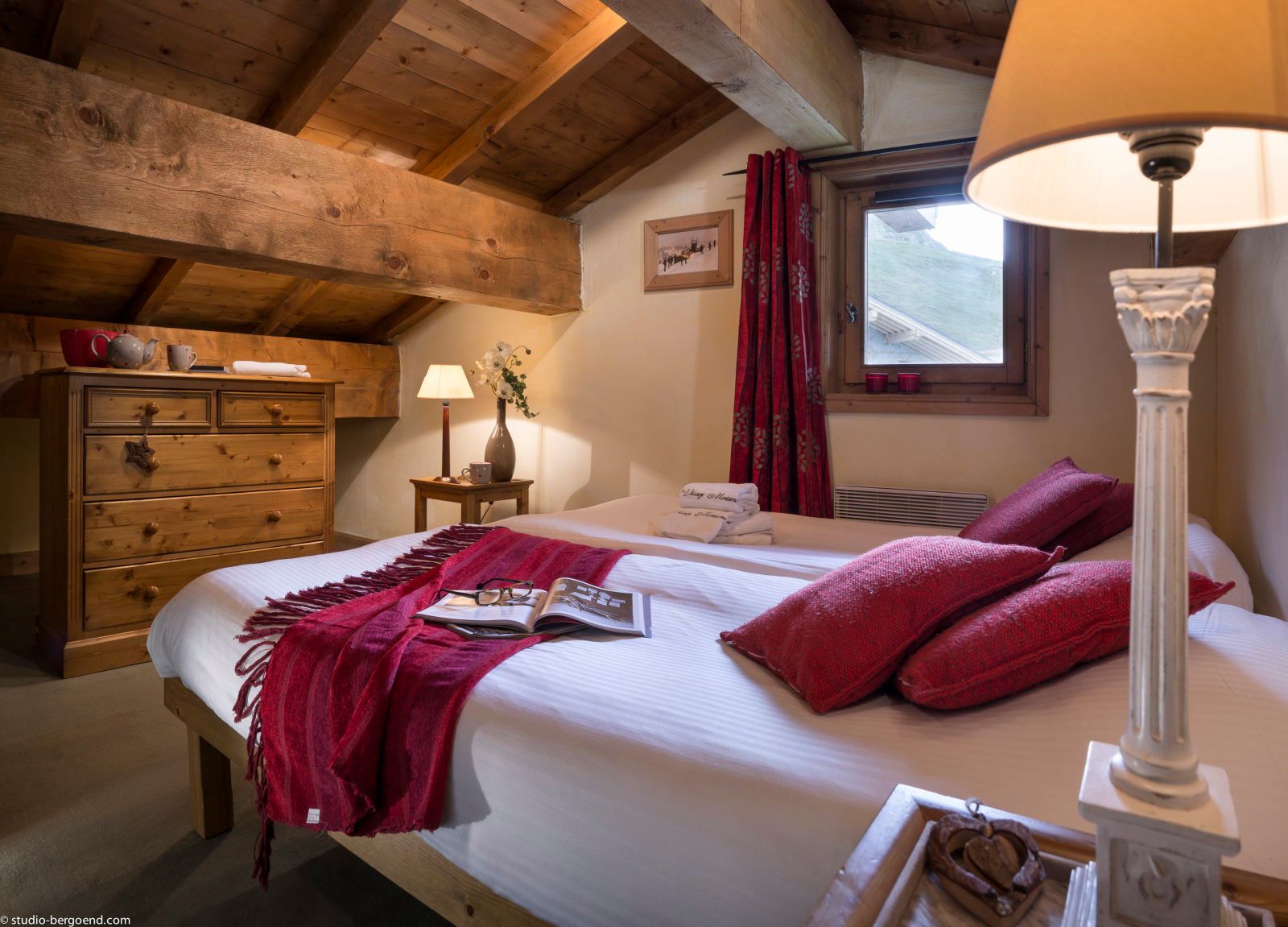 image Attic bedroom with a sloped wooden ceiling, double bed, and decorative lamps — a charming hideaway