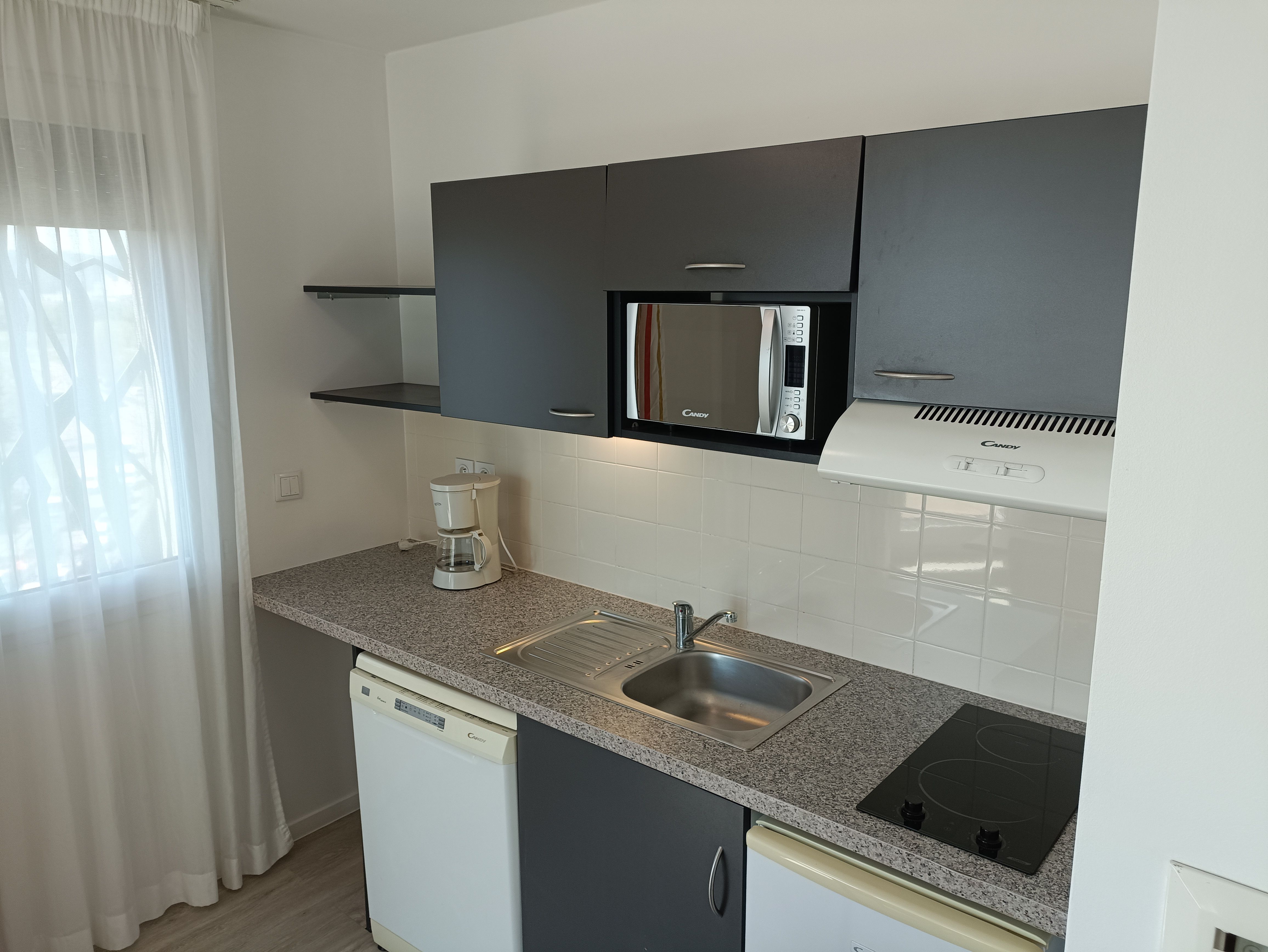 image This bright kitchen setup is complete with essential appliances, ample counter space, and a welcoming atmosphere, ideal for your culinary adventures.