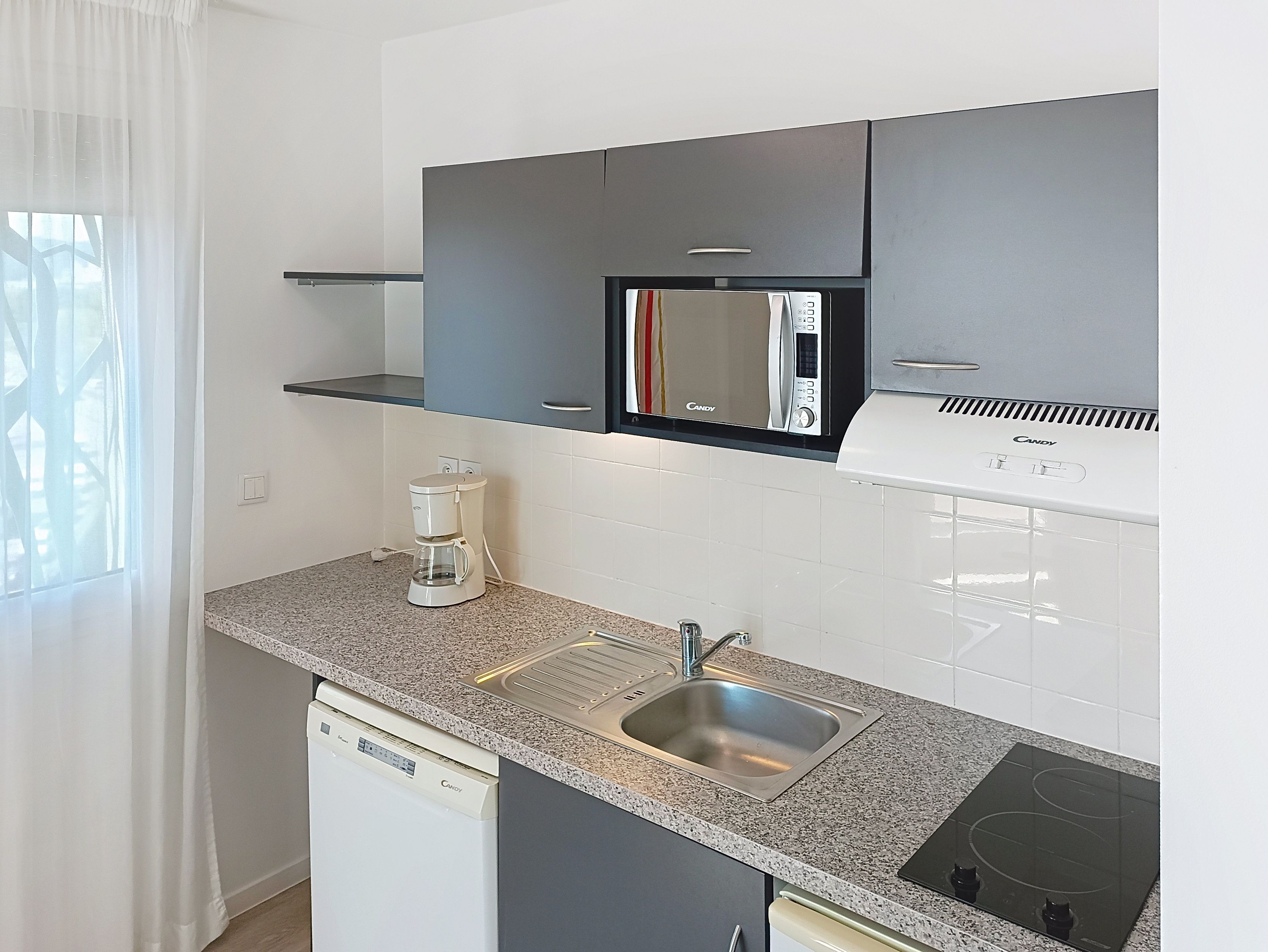 image Kitchen with sink, appliances, and window with curtains.