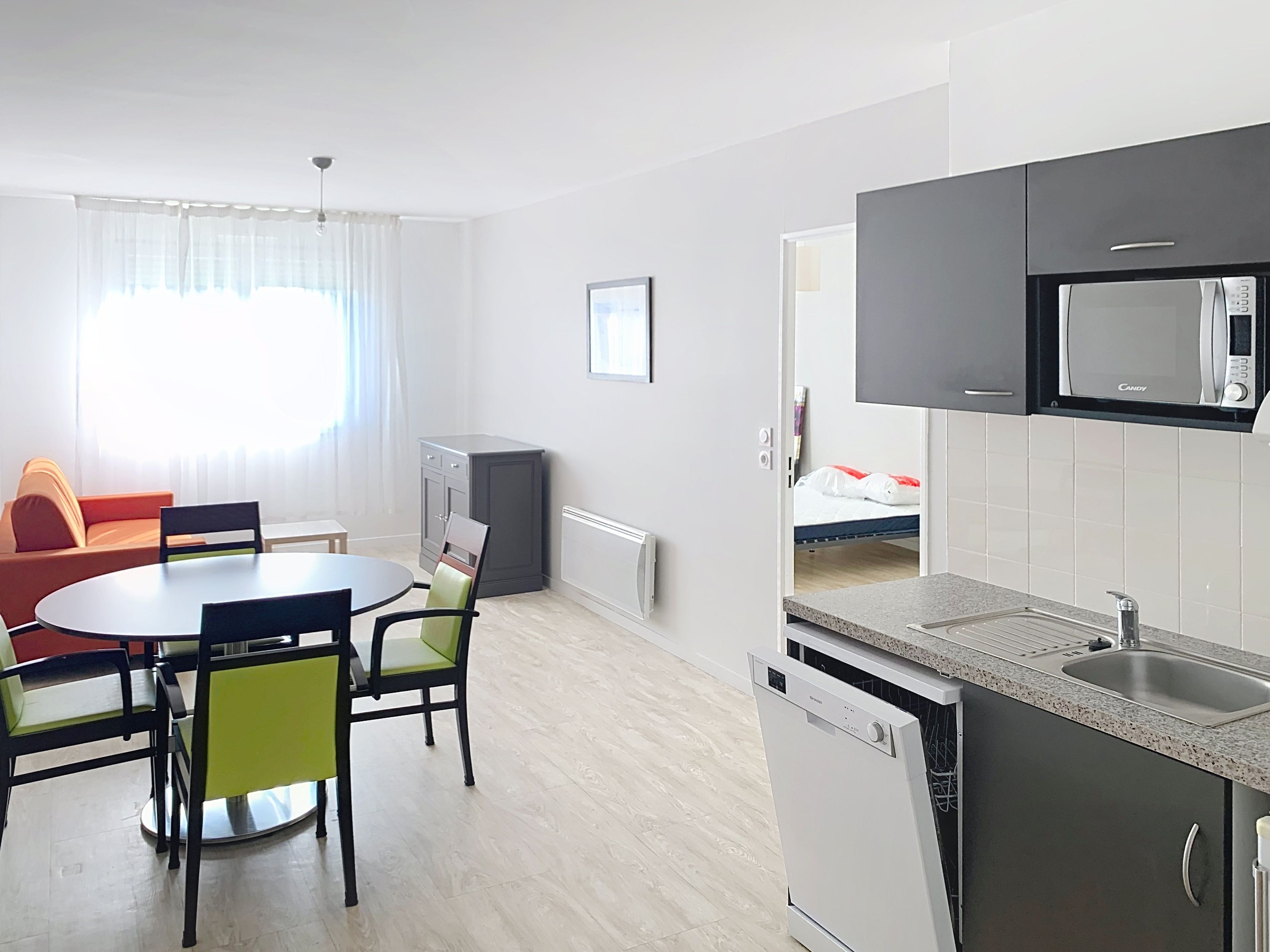 image Open plan kitchen and living area with dining table and green accent chairs.