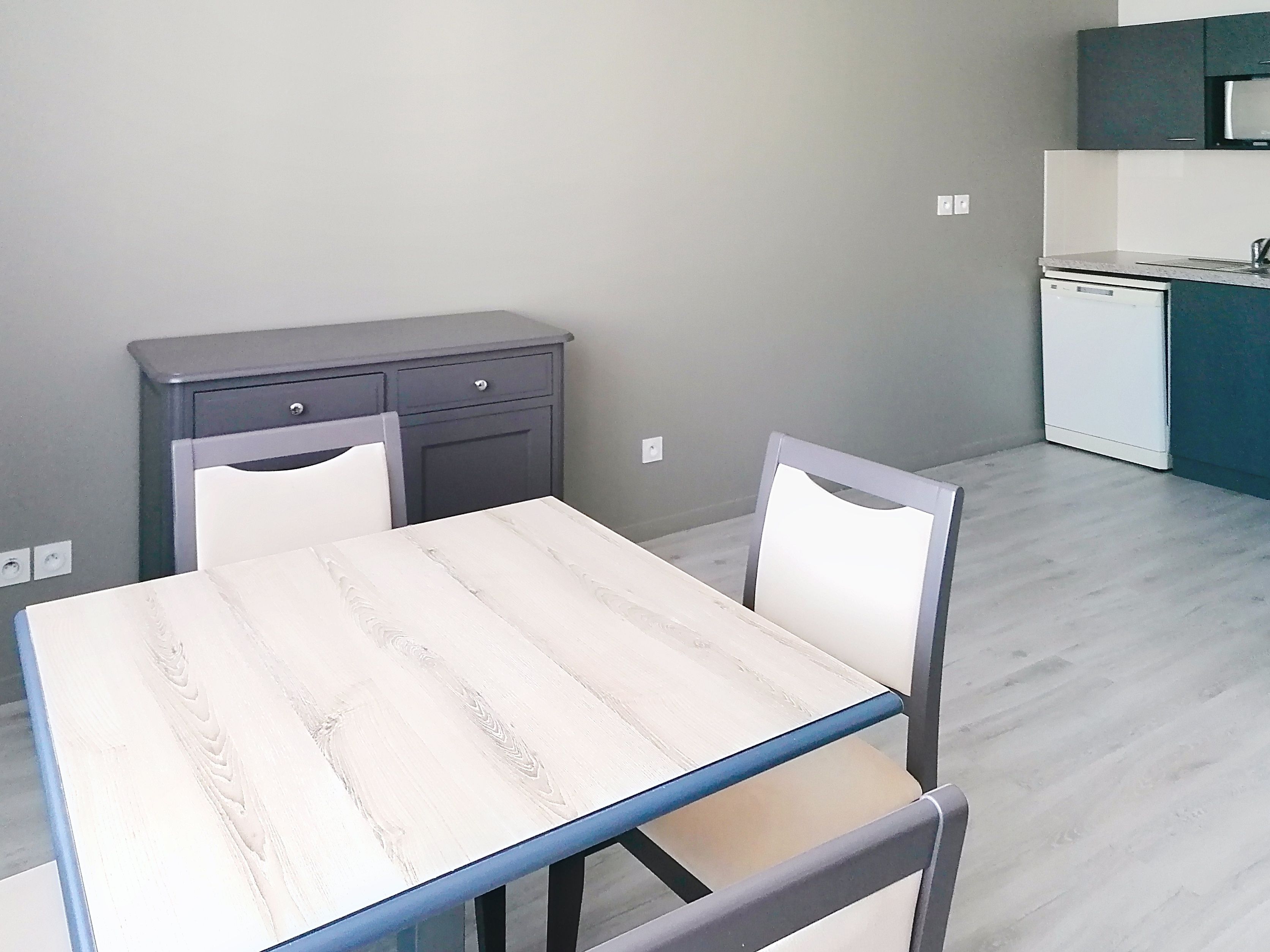 image Open plan dining and kitchen area with modern appliances and dining table.
