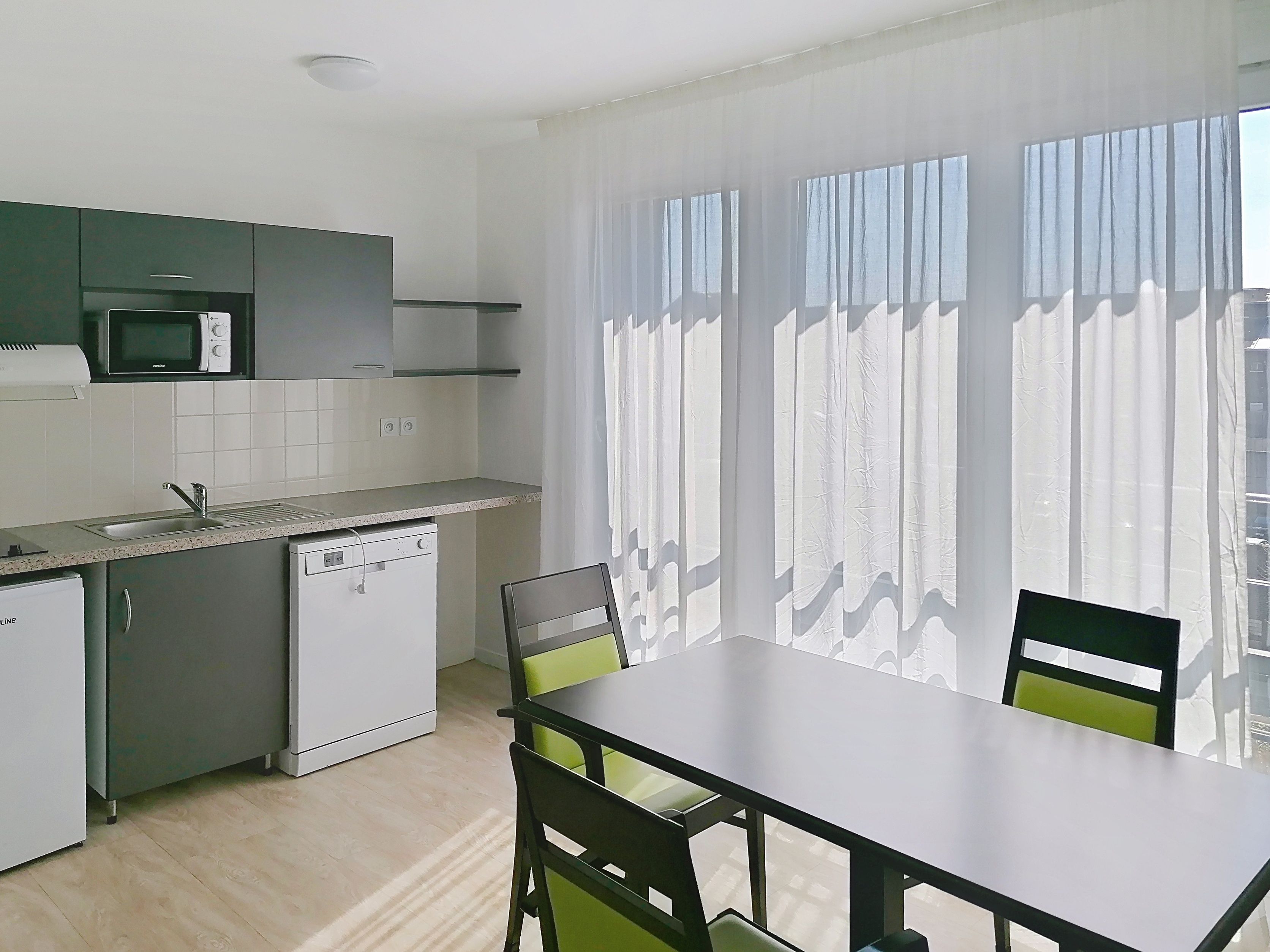 image Kitchen with appliances, countertop, and dining table with chairs.