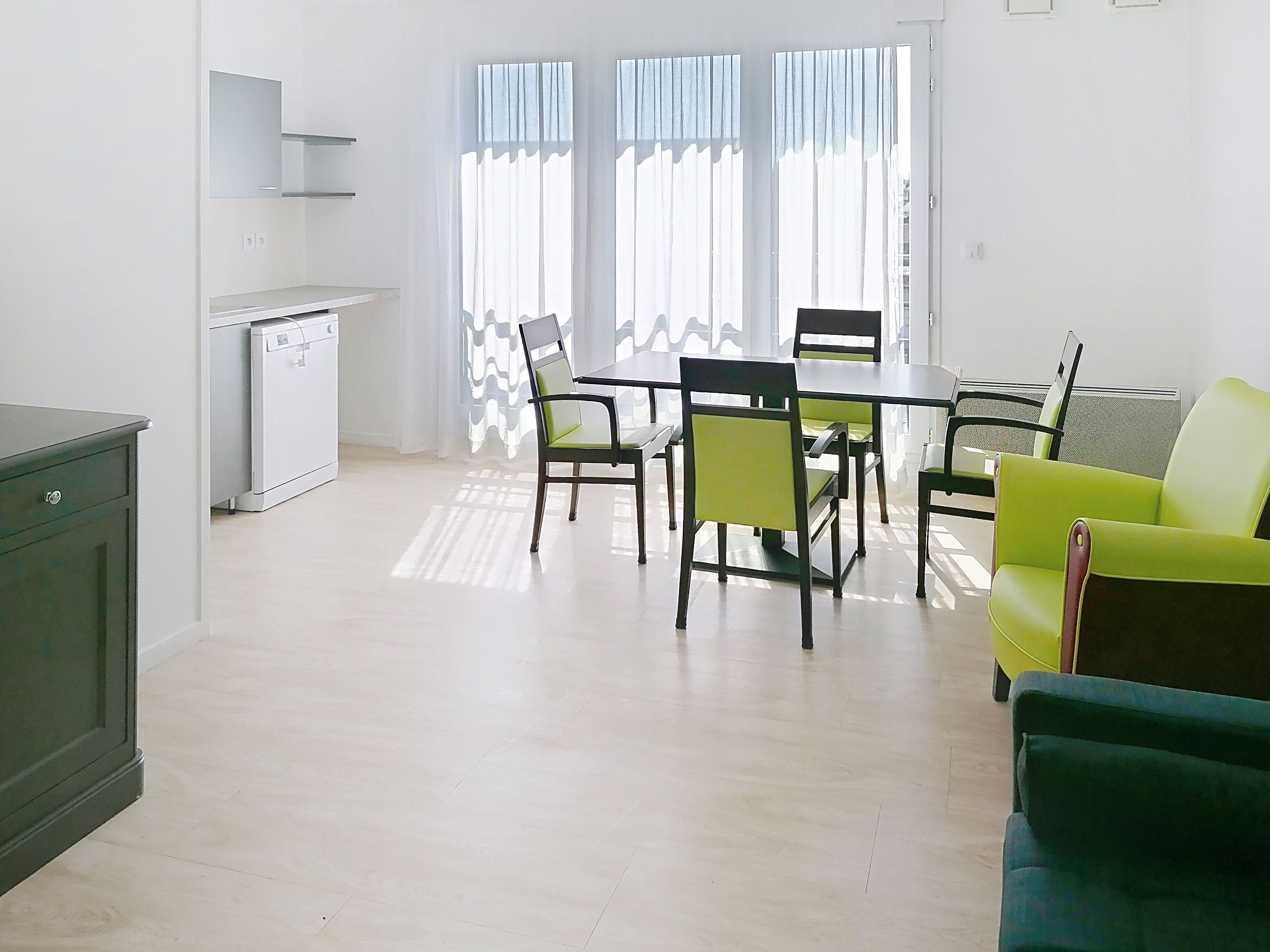 image Kitchen area, dining table, and large windows with curtains.