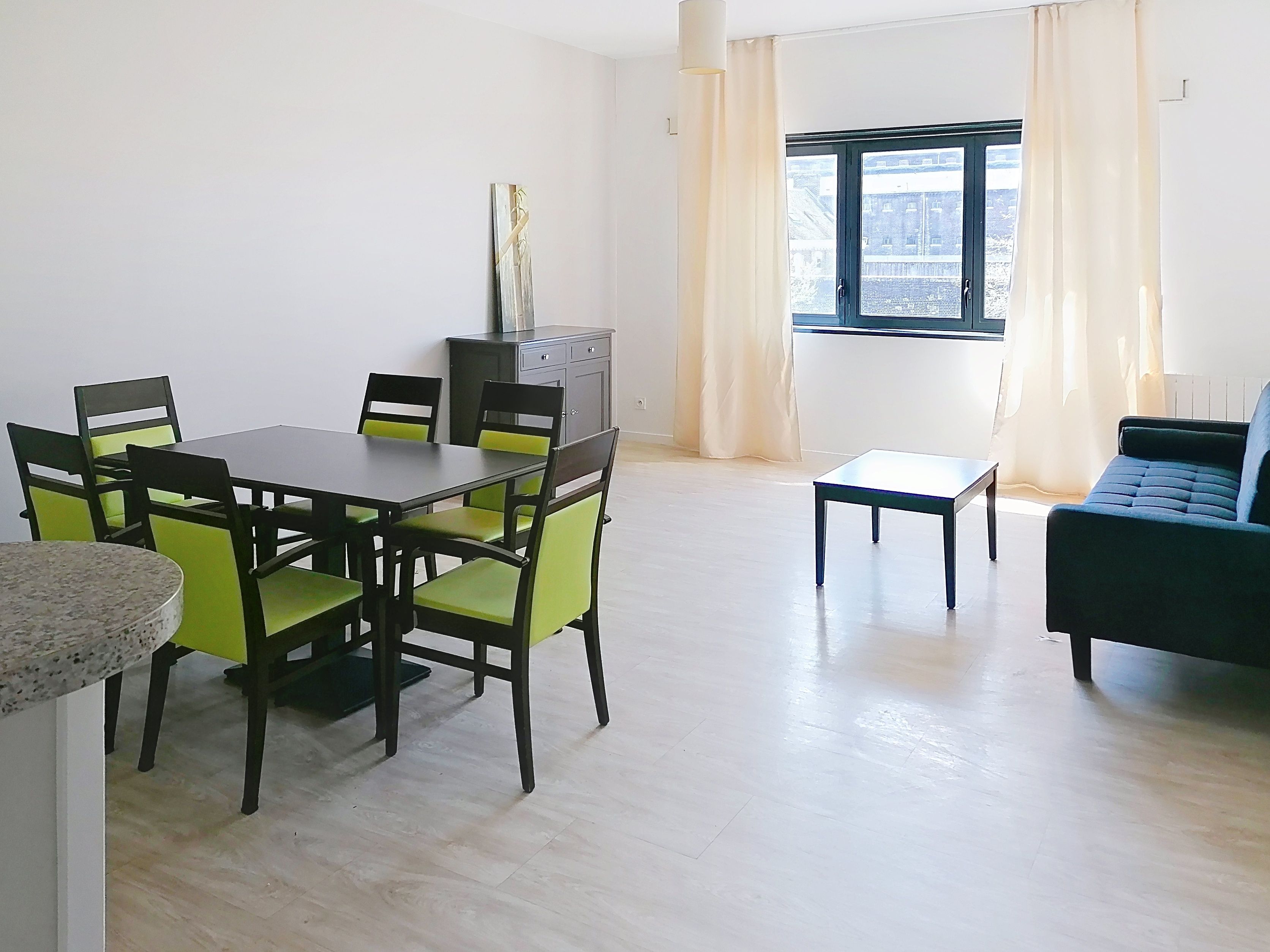 image Dining table with green chairs, gray sideboard, and blue sofa.