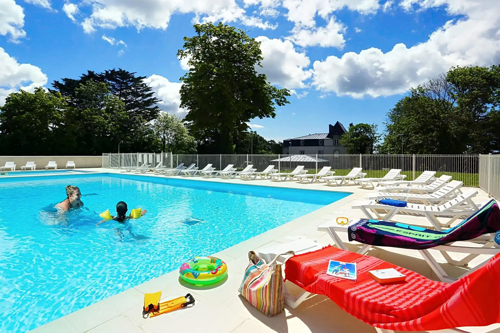 image Families enjoy the sun and fun at the outdoor heated pool, surrounded by lounge chairs and lush greenery.