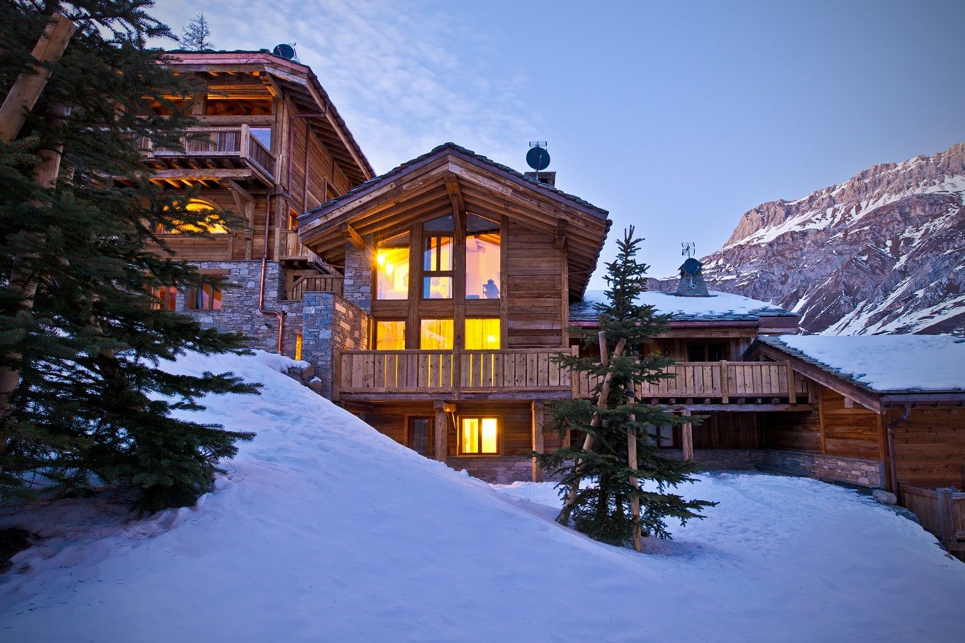 image This luxurious chalet exudes rustic charm, showcasing a stunning exterior with warm lighting that complements the surrounding snowy landscape and majestic mountains.