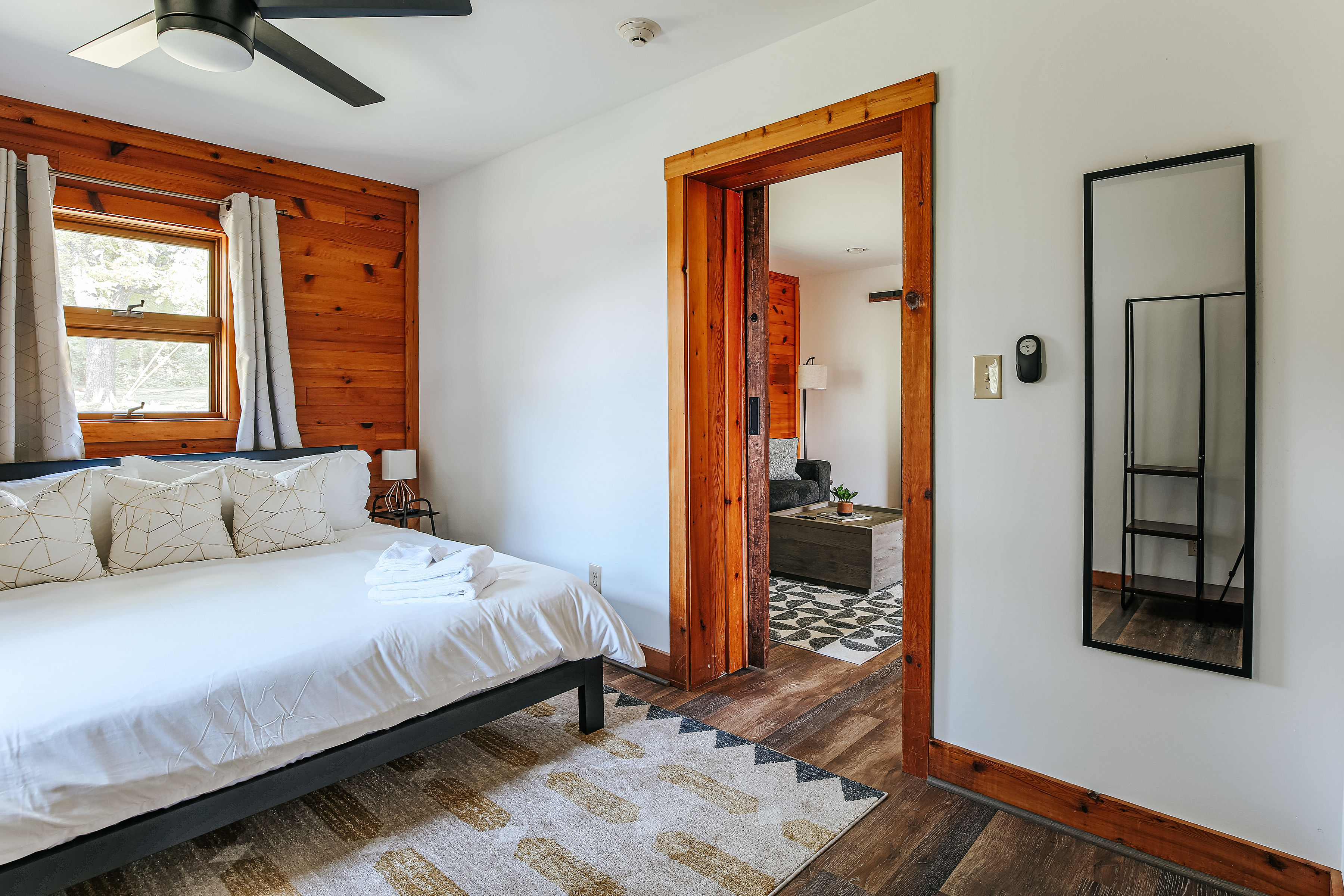 image Cozy bedroom retreat with warm wood accents, a king bed, and a full-length mirror.