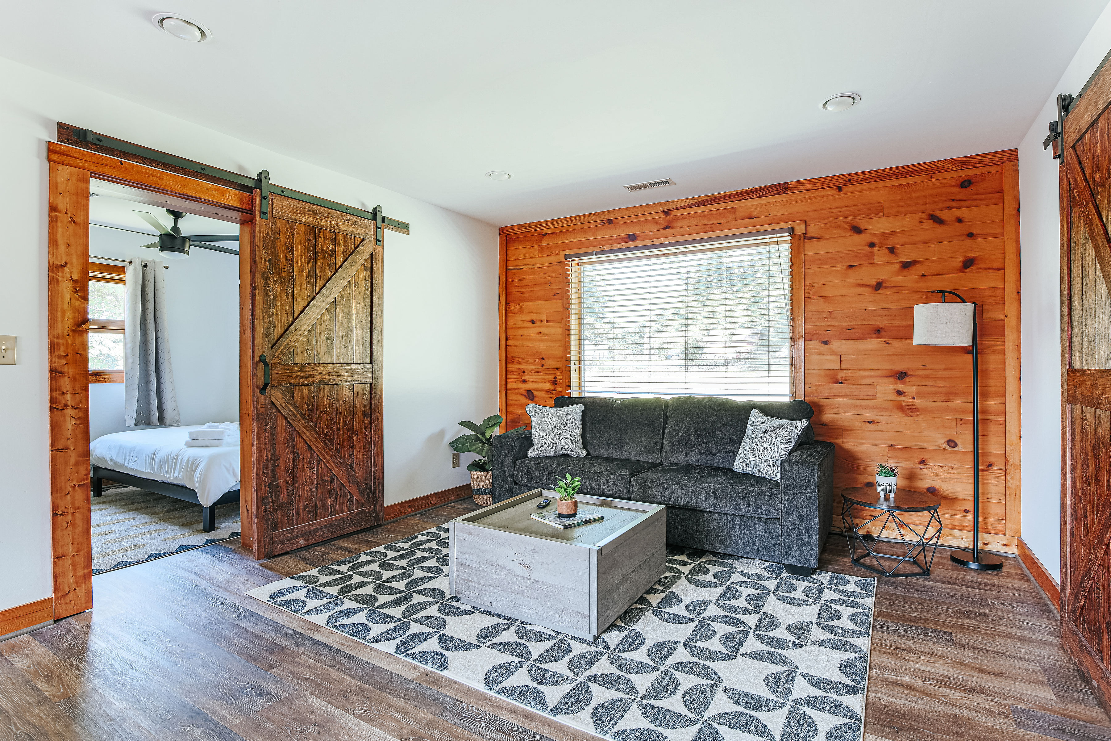 image Enjoy the charm of rustic wood accents in the spacious living room, featuring a queen pull-out sofa, stylish coffee table, and large windows that fill the space with natural light.