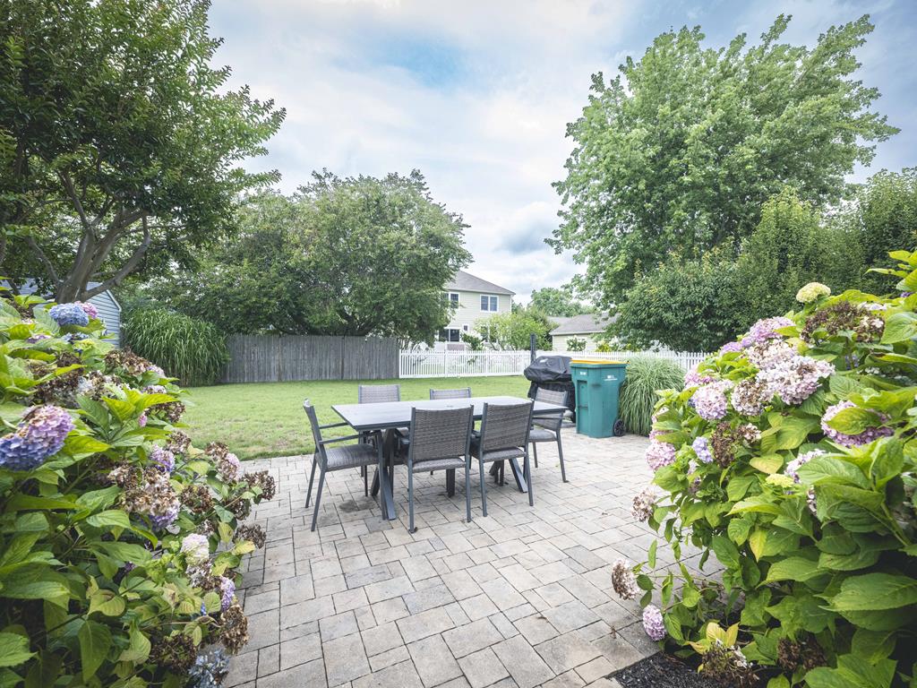 image The outdoor dining in the spacious backyard, surrounded by lush greenery and vibrant hydrangeas, is perfect for family gatherings and summer barbecues.