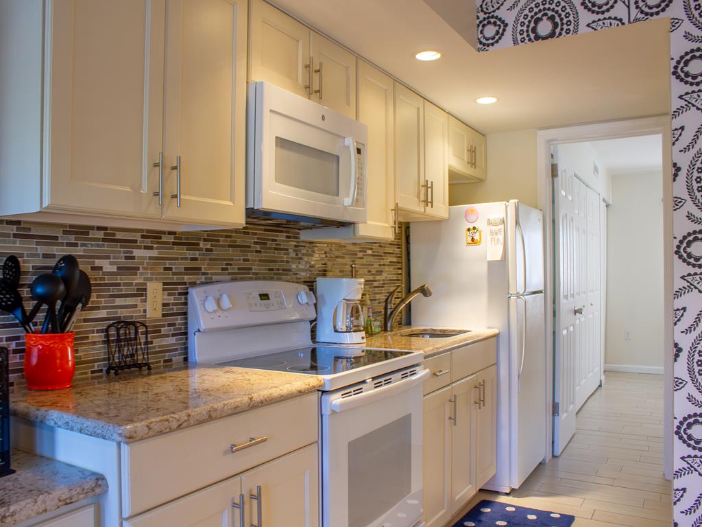 image Modern full kitchen with updated finishes and ample counter space, perfect for family meals before the beach or pool.