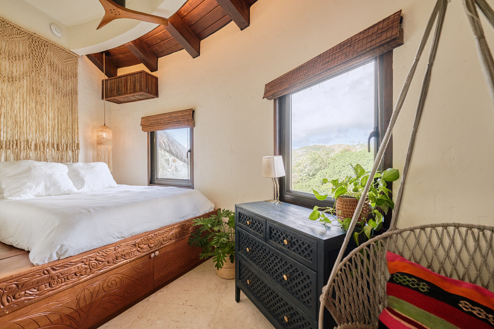 image Rustic-chic bedroom with exposed beams, woven headboard, and sweeping views of tropical greenery.