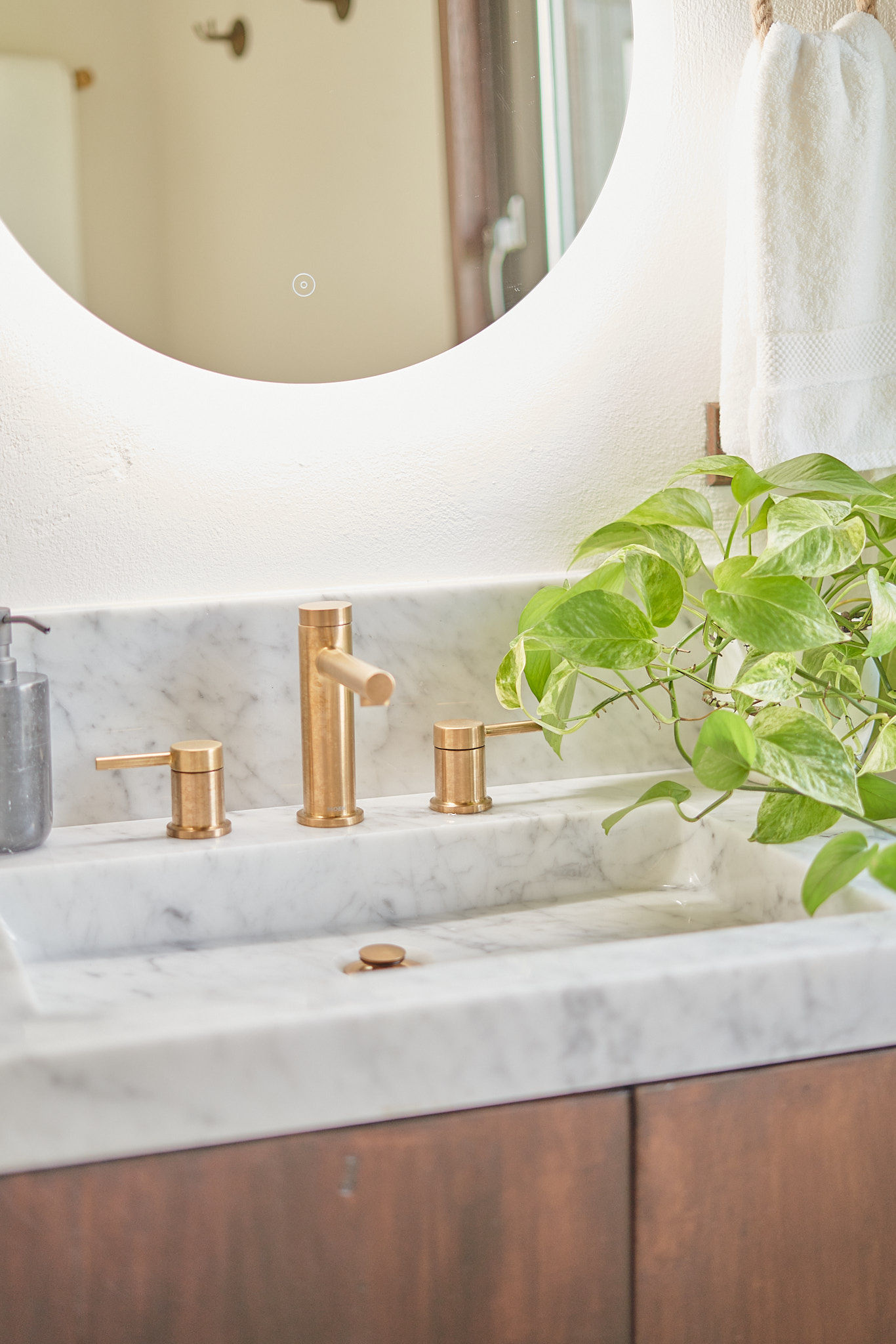 image Sleek bathroom vanity with warm brass fixtures and a touch of greenery.